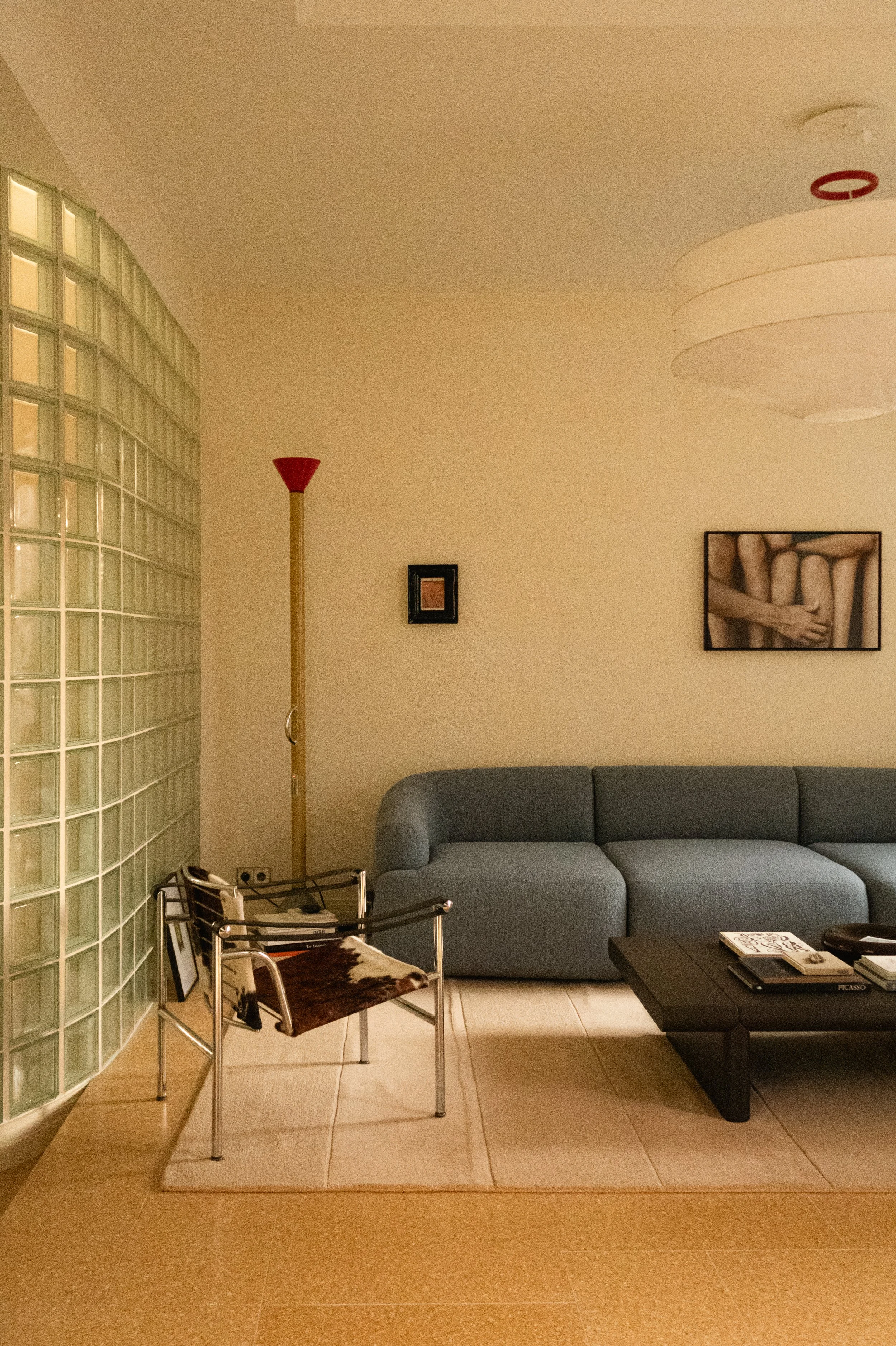 Salon moderne avec un canapé design bleu bouclette, une table basse de designer coloris marron espresso, une lampe sur pied, et des œuvres d'art sur le mur.