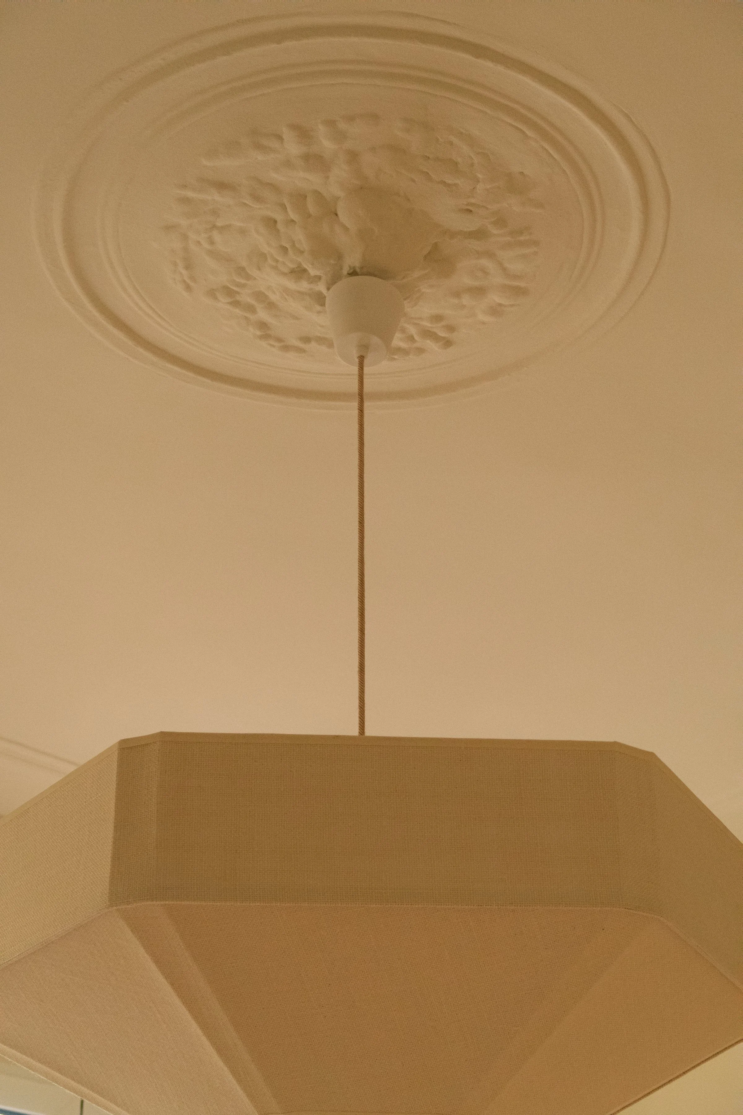 Lampe suspendue rectangulaire beige avec plafonnier de plâtre orné de motifs.