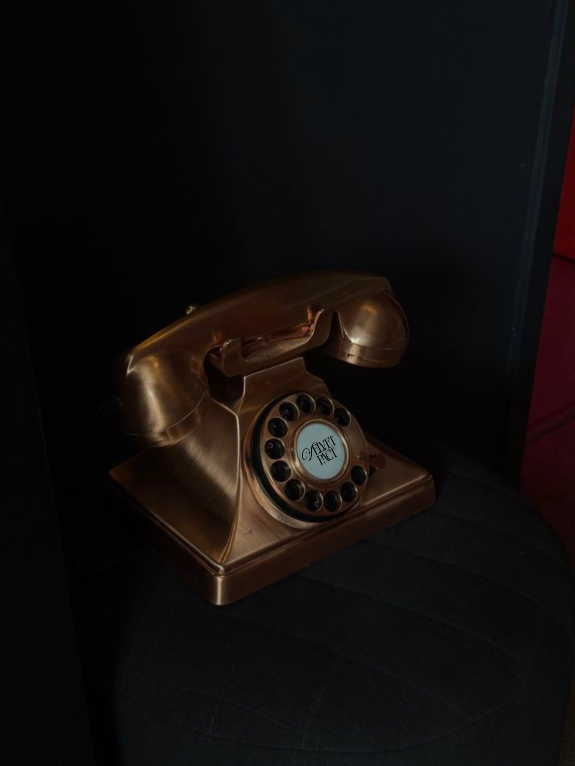 Téléphone vintage en métal doré, posé sur un siège noir.