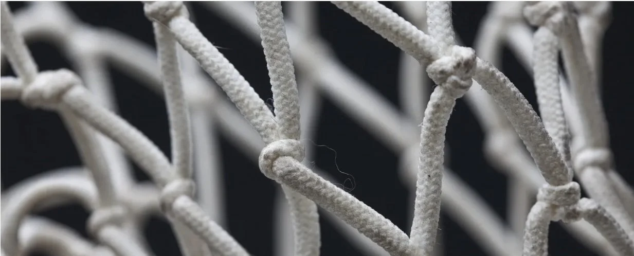 Close-up of white intertwined ropes or strings forming a complex pattern.