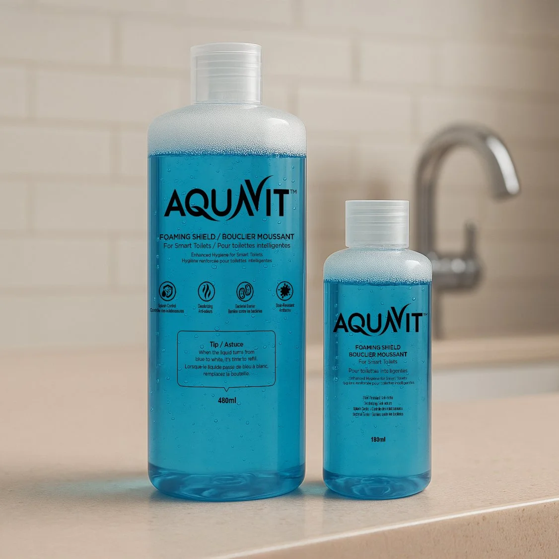 Two bottles of AQUAVIT foaming toilet cleaner with blue liquid on a bathroom countertop, with a blurred sink faucet in the background.
