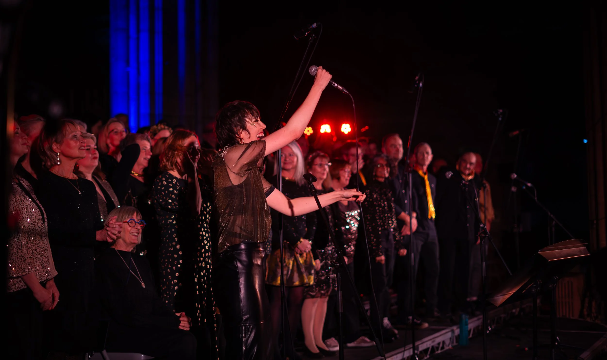 Joyful close-up of a Soul of the City Choir singer smiling and taking the mic during a live performance.