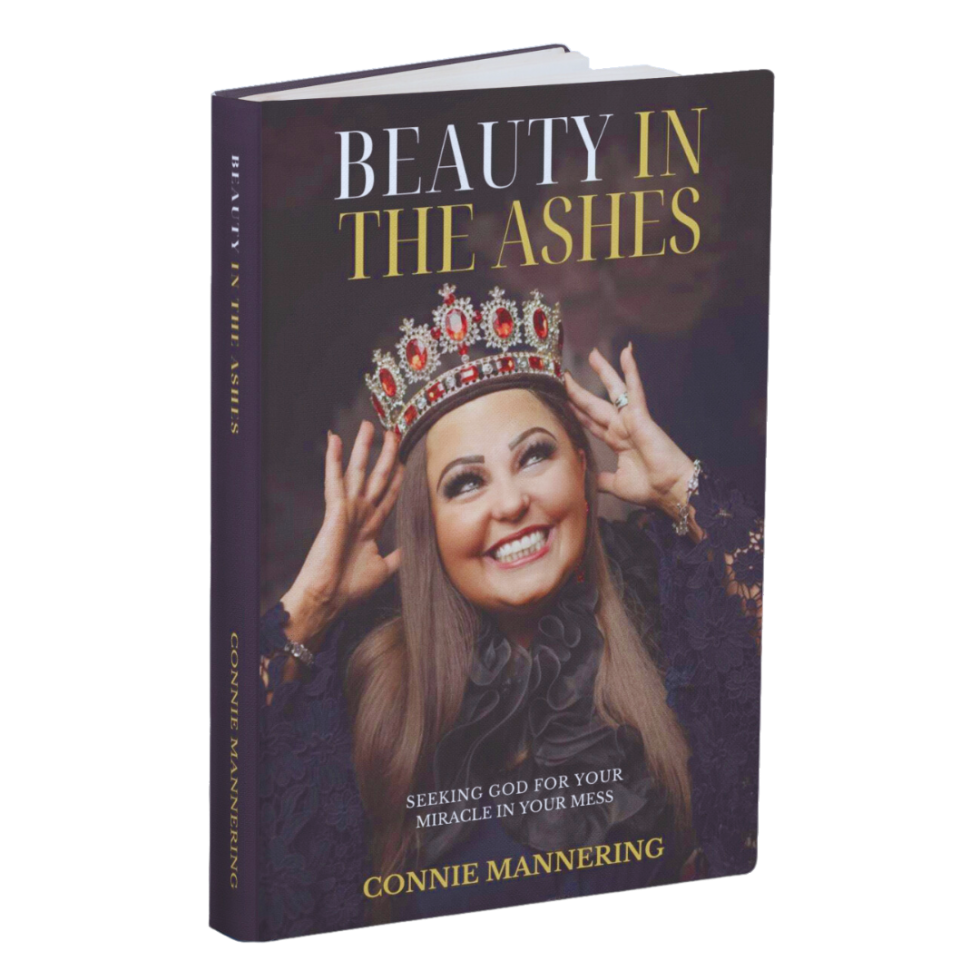 Book titled "Beauty in the Ashes" by Connie Mannering, featuring a smiling woman wearing a crown and dark lace attire.