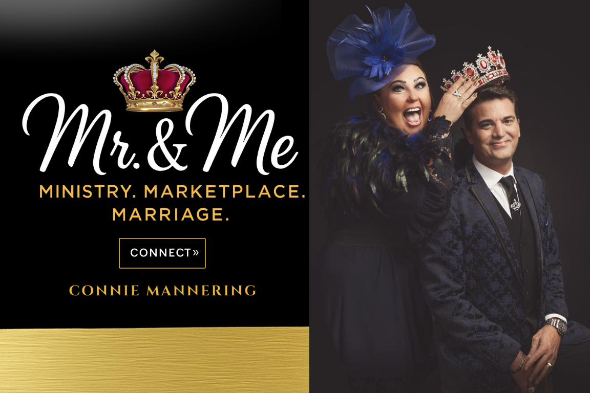 A woman and a man dressed in formal attire, wearing crowns and a large blue hat, smiling and celebrating, with a dark background.