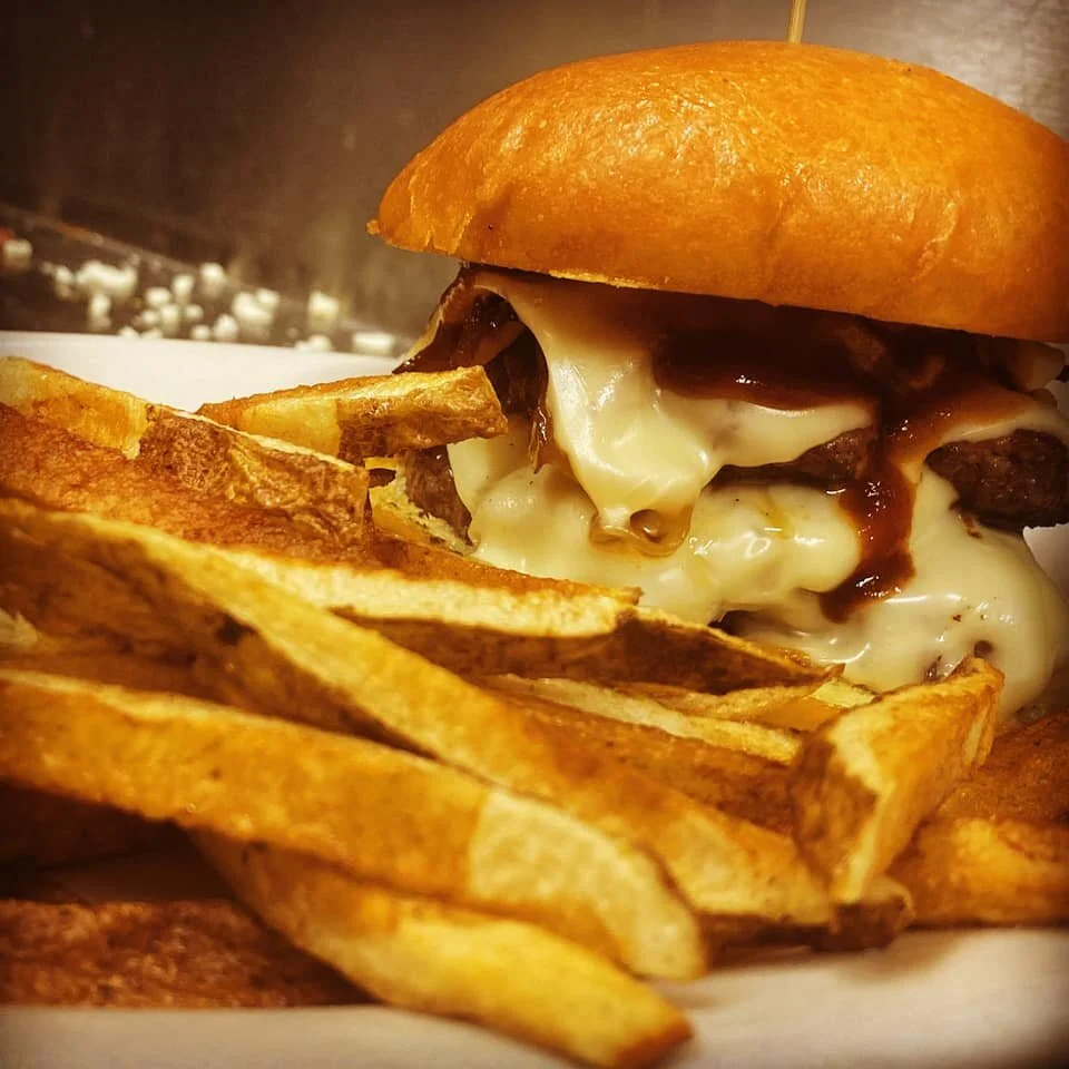 Close-up of cheeseburger with fries on a plate.