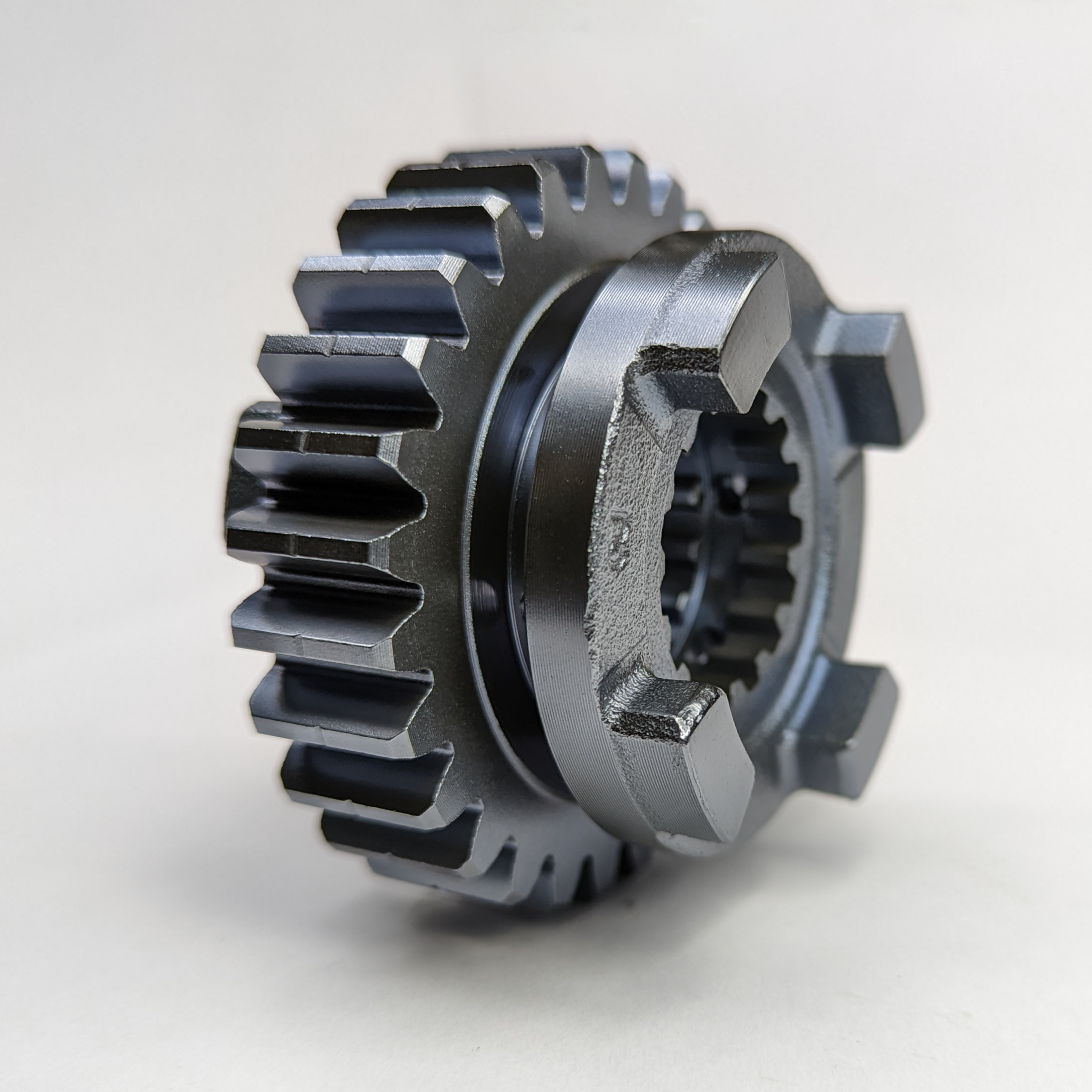 A metallic gear with evenly spaced teeth, isolated on a plain background, coated in tungsten disulfide.
