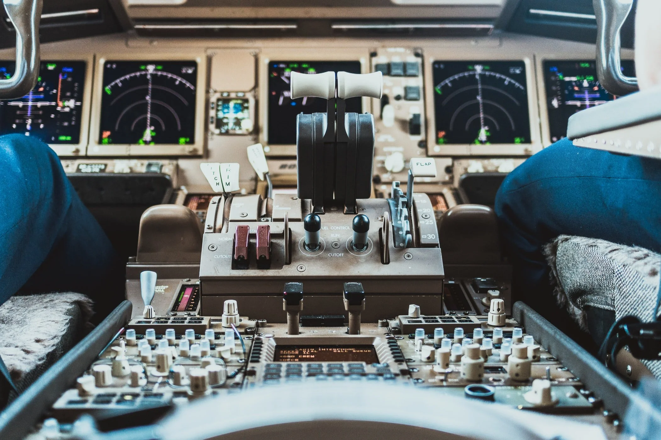 Inside the cockpit of an aircraft, showing the control yoke, multiple navigation displays, and various flight instruments and controls.