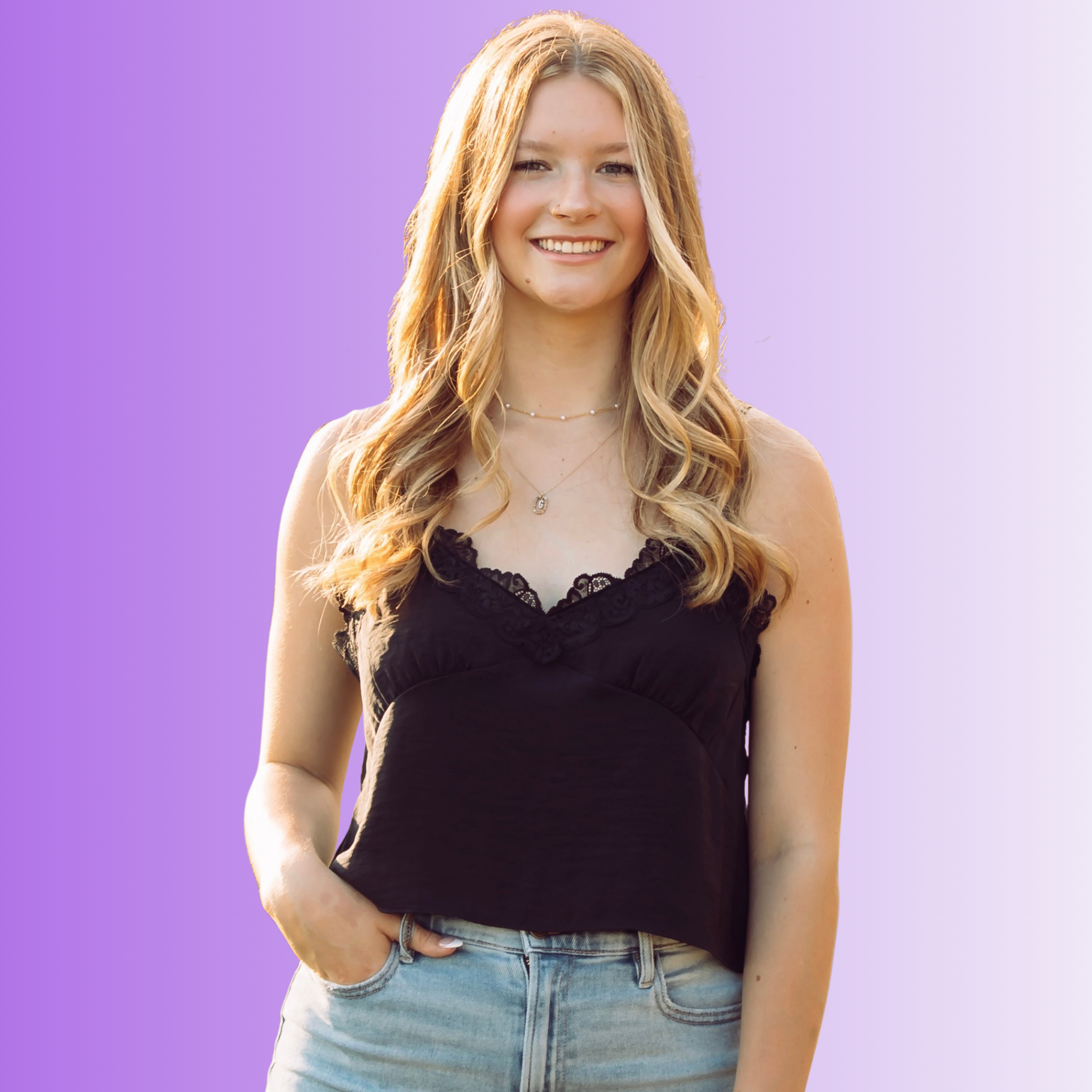 A young woman with long, wavy blonde hair, wearing a black sleeveless top and light blue jeans, smiling outdoors on a sunny day with a pink gradient background.