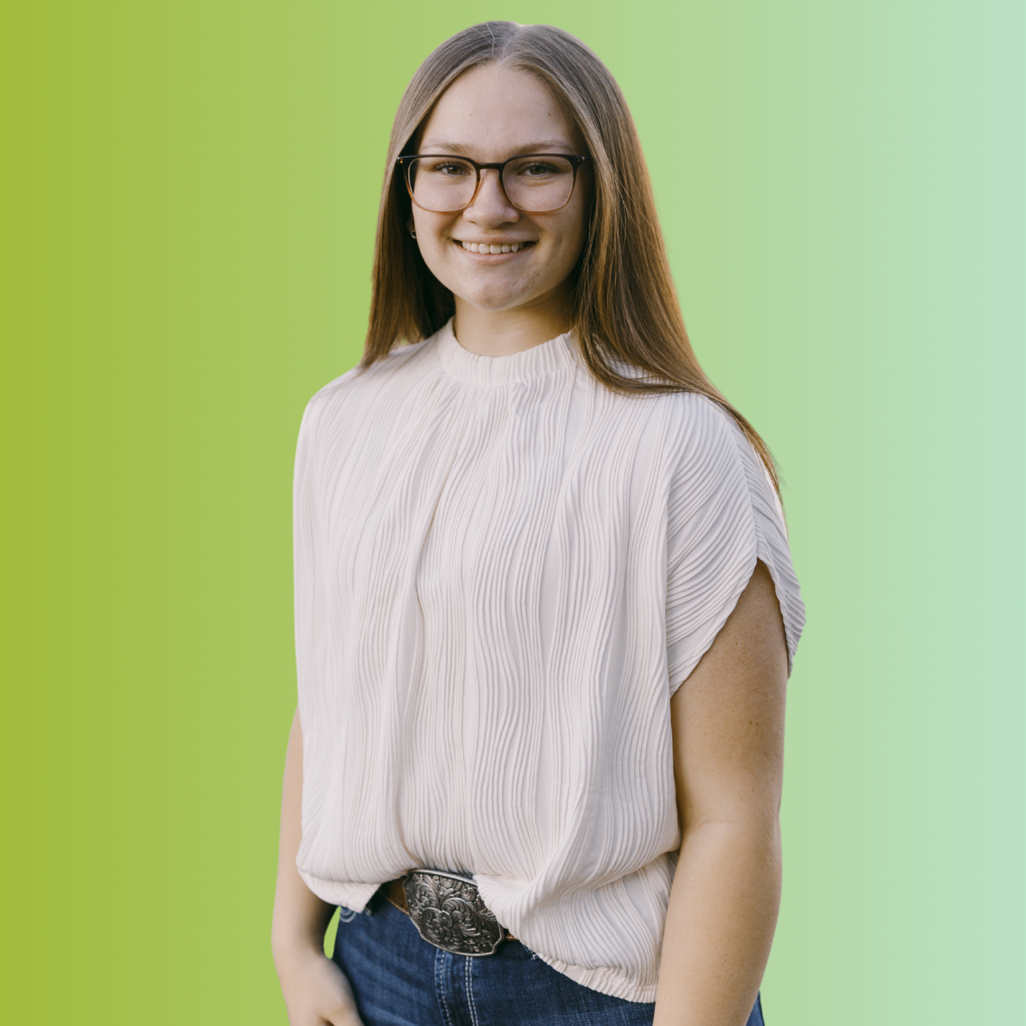 A young woman with long brown hair, glasses, and a white pleated blouse smiling against a green background.