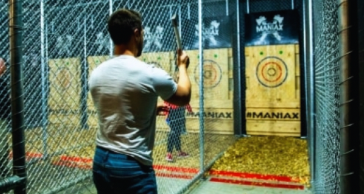 Person playing axe-throwing game at an indoor amusement center.