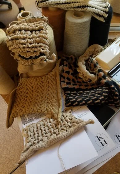 Various yarns and partially completed knitted and crocheted samples on a wooden surface.