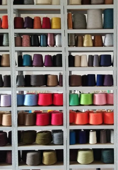 Shelf filled with rows of colourful yarn in a creative knitwear studio.