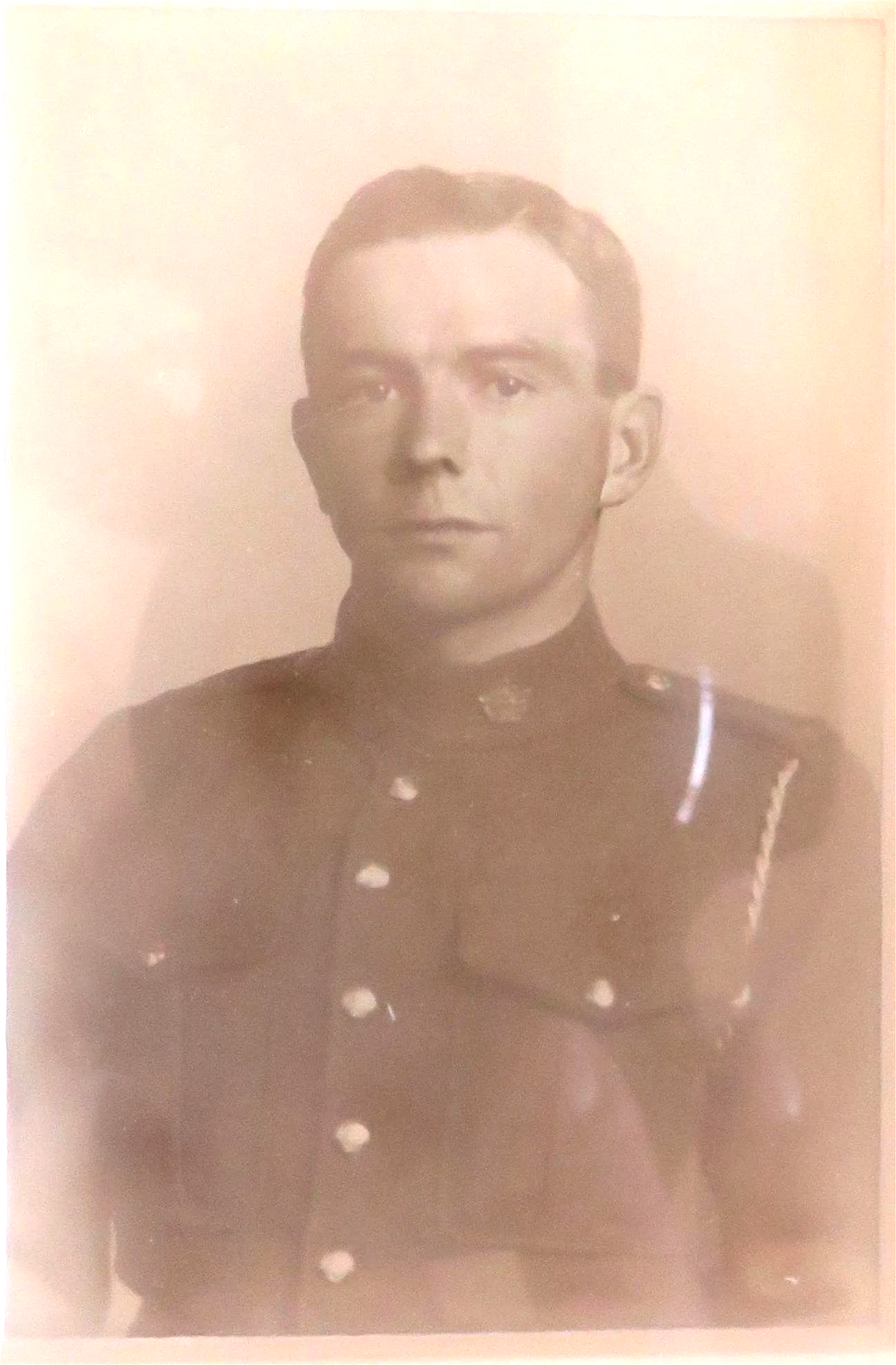Black and white portrait of a young man in a military uniform, looking directly at the camera with a serious expression.