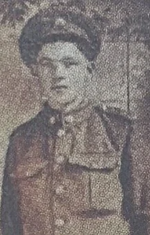Black and white photo of a man in a military uniform with a cap, standing outdoors.