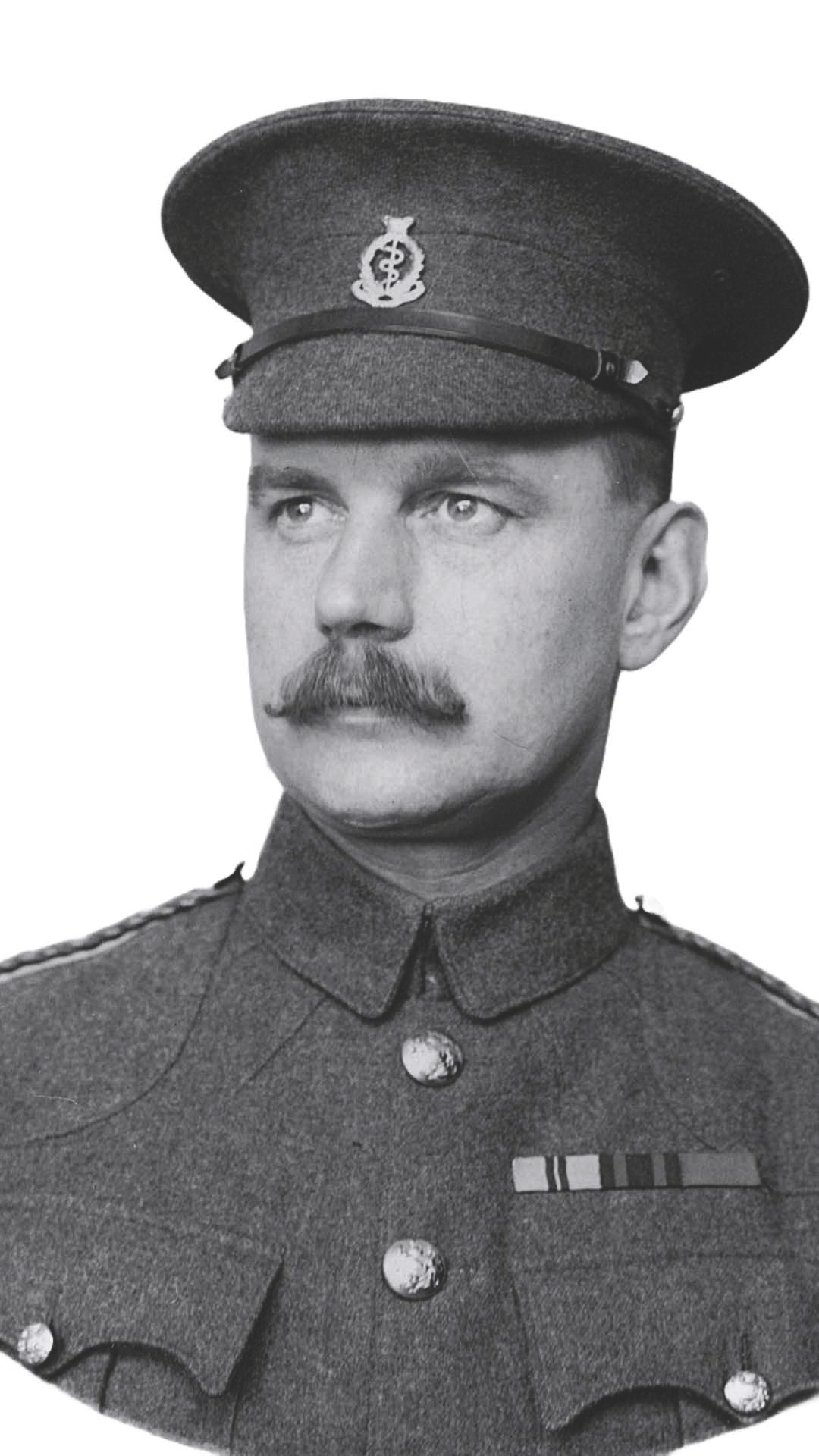 Black and white photo of a man in a military uniform, wearing a cap with a badge, mustache, and decorated uniform with medals.