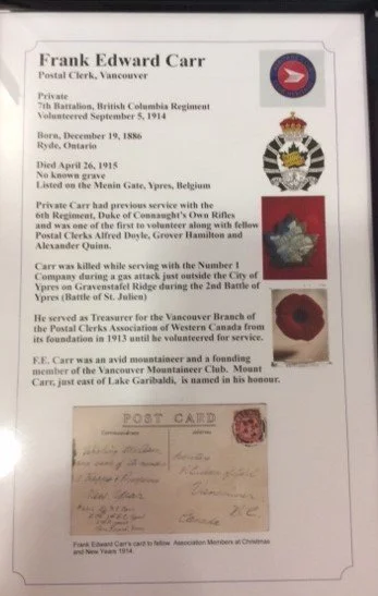 A collection of military insignia, a poppy flower, and a vintage postcard, along with a business card for Frank Edward Carr, Postal Clerk, Vancouver.