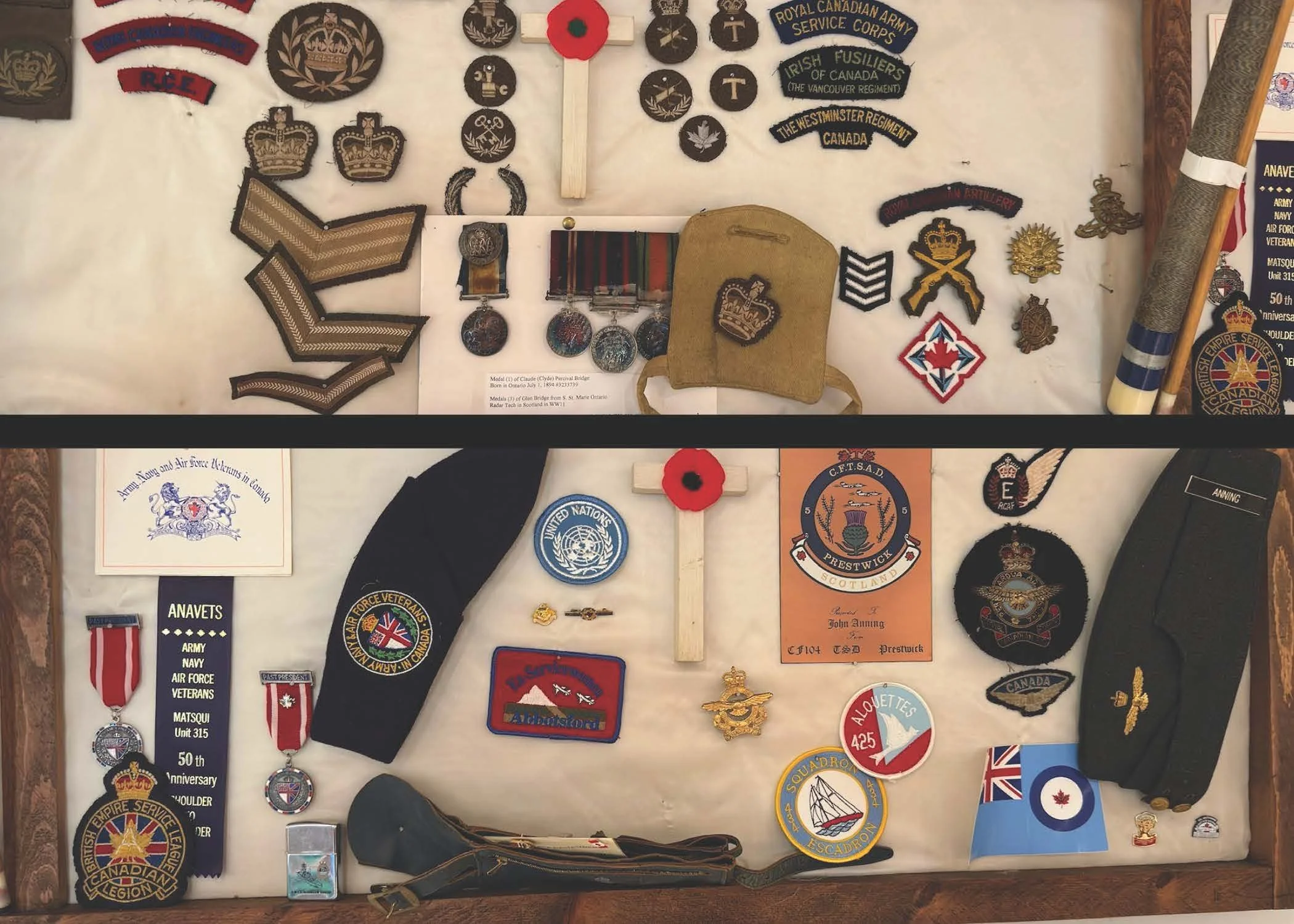 Display of military patches, medals, insignias, pins, uniform patches, a small flag, a cap, and other military memorabilia related to Canadian armed forces and veterans.