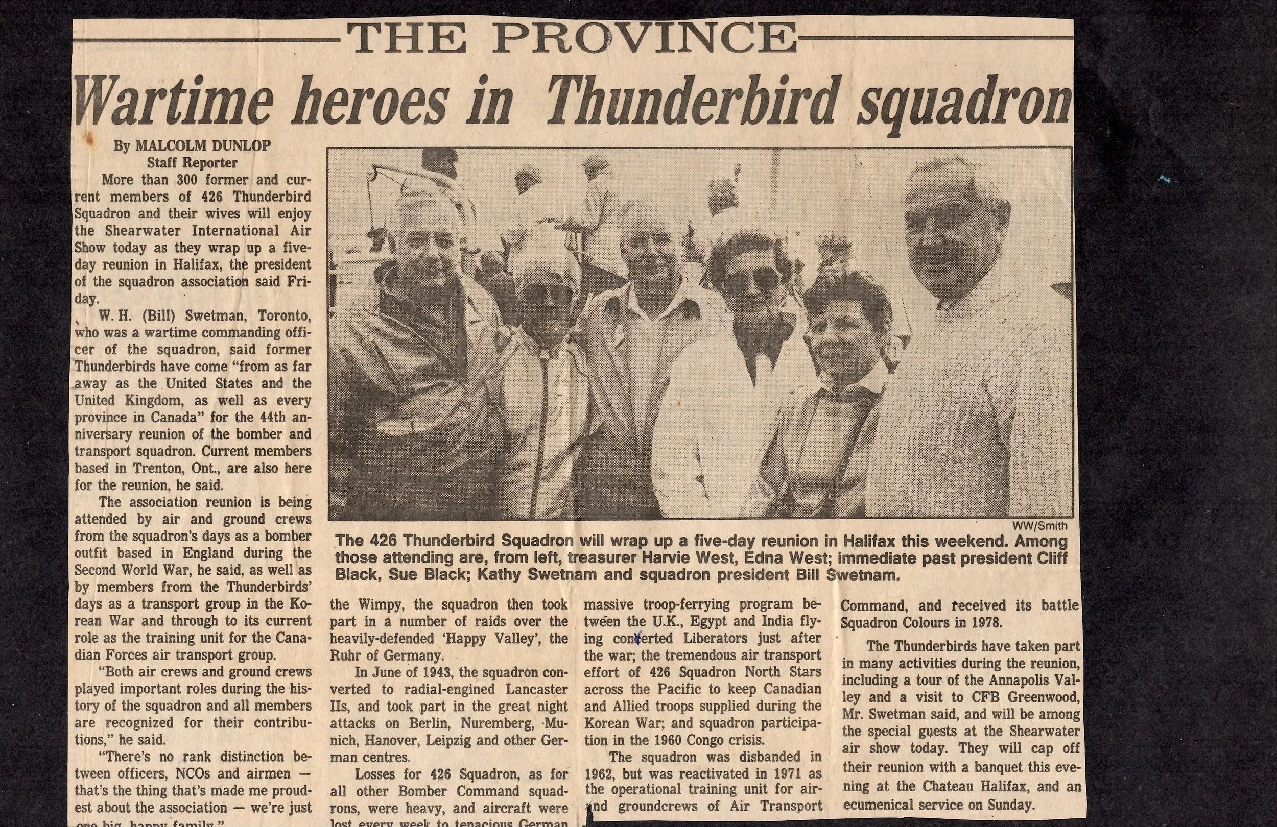 Black and white newspaper clipping of a photograph showing a group of seven men standing outdoors, dressed in casual and military-style clothing, with some wearing sunglasses. The headline reads "Wartime heroes in Thunderbird squadron." The article d