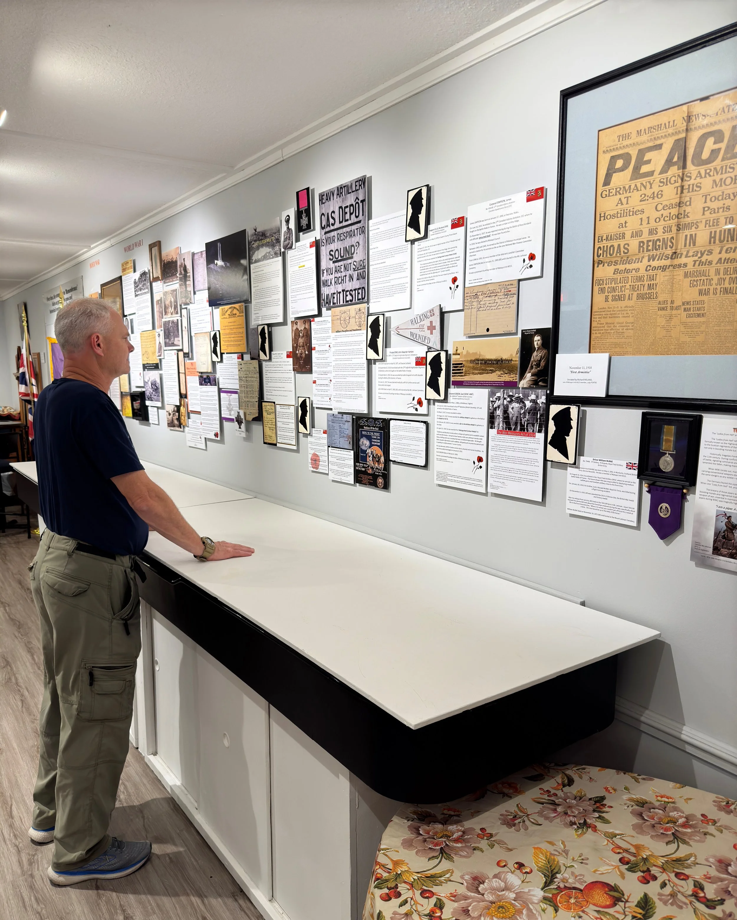 Man standing in front of a museum display wall with historical documents and photographs.
