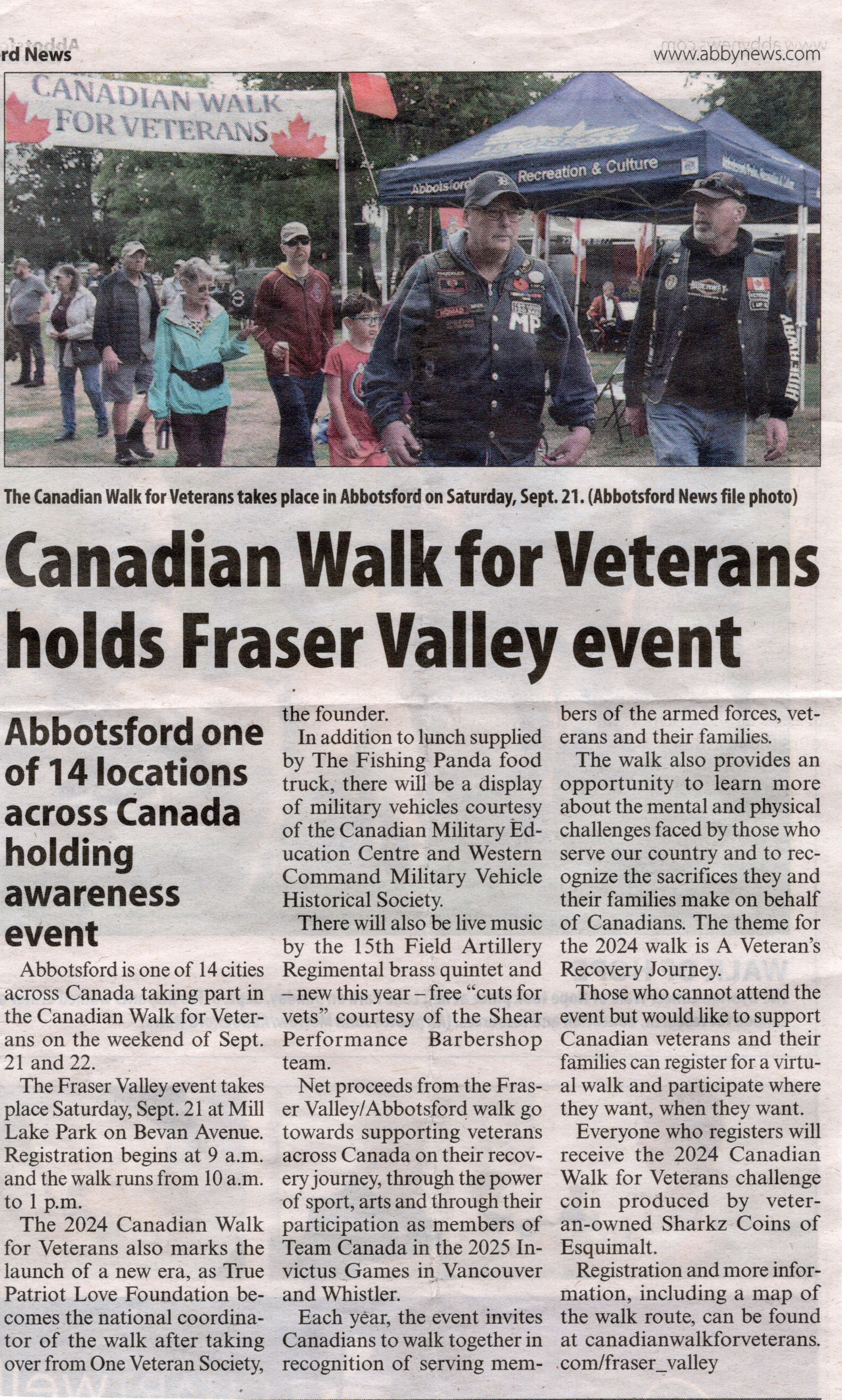 A group of people, including veterans wearing jackets with patches, participating in the Canadian Walk for Veterans event at Mill Lake Park in Abbotsford, with a banner reading "Canadian Walk for Veterans" and a blue tent in the background.