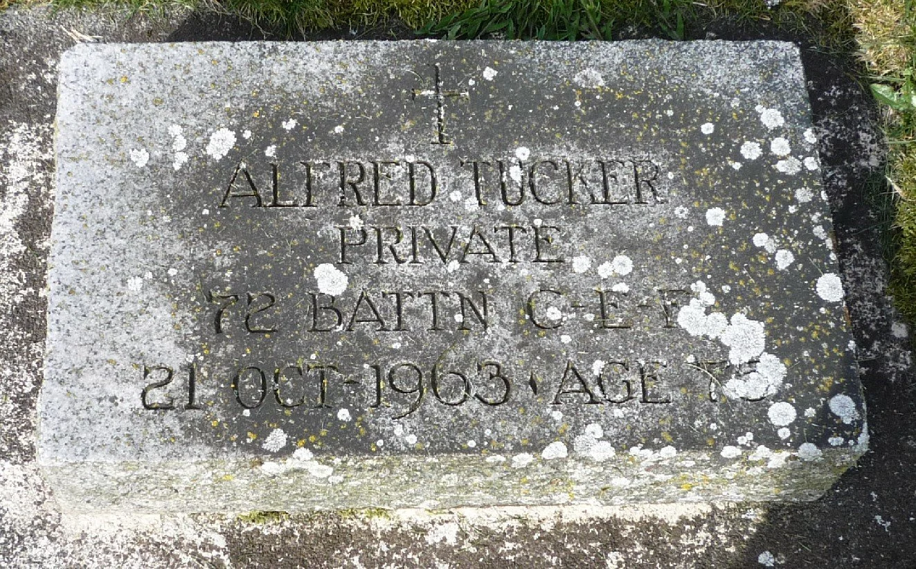 Gravestone with the inscription: "In memory of All Red Tucker Private 72 BATN C. E. 21 OCT 1963 AGE 63" surrounded by moss and lichen.