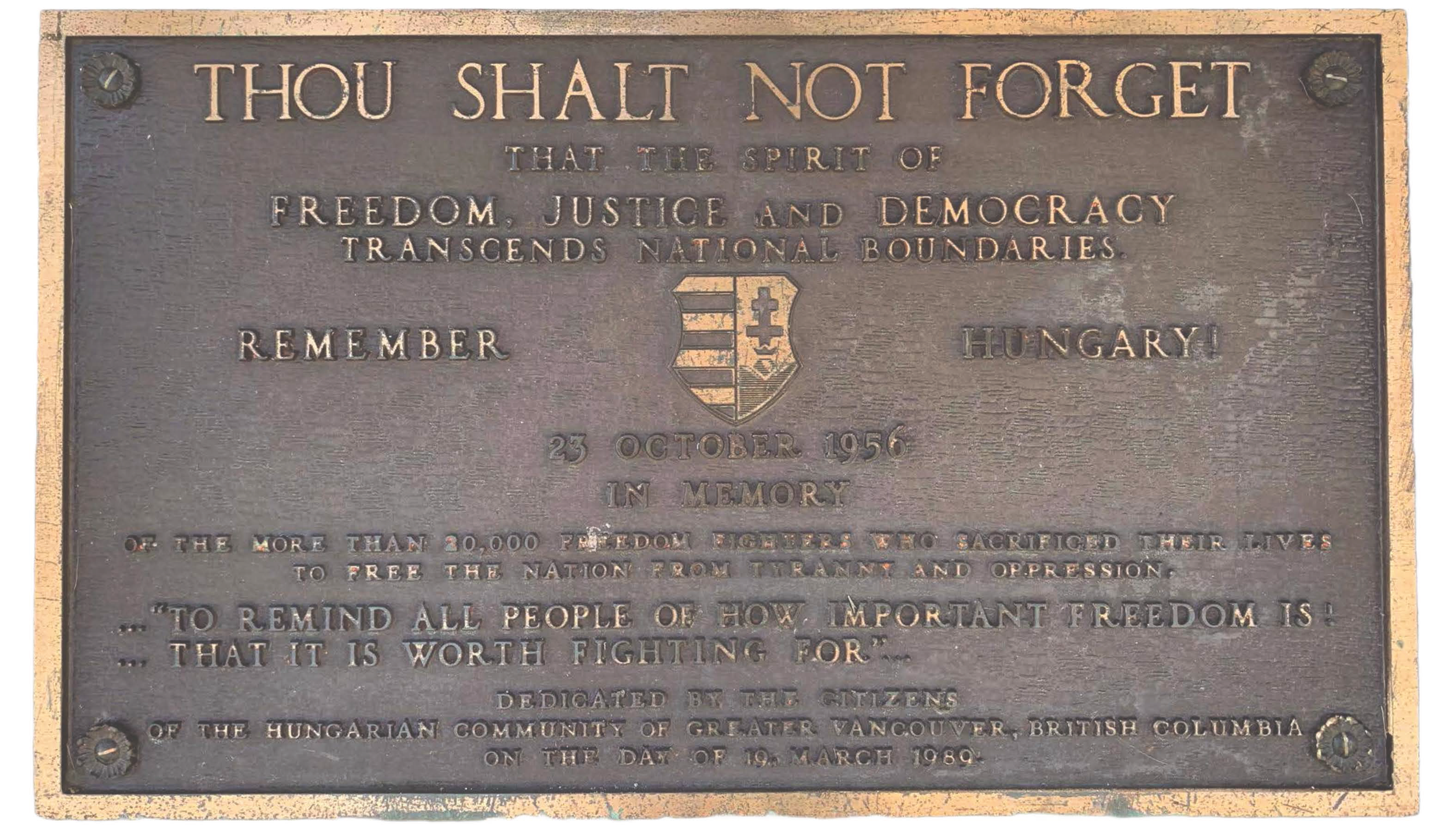 A commemorative bronze plaque with a border, honoring the memory of freedom fighters who sacrificed their lives on October 23, 1956, in Hungary. The plaque features a shield emblem in the center and text urging remembrance of the importance of freedom, dedicated by Hungarian citizens of Vancouver, British Columbia, on March 19, 1989.