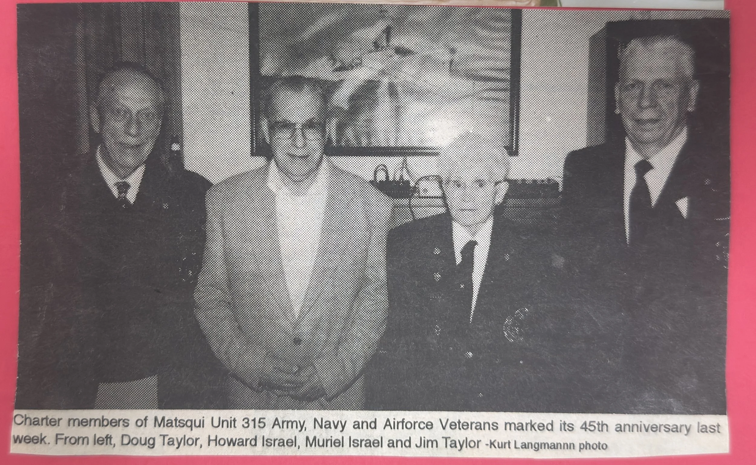 Black and white photo of four men standing indoors, dressed in formal military and civilian attire, with a painting on the wall behind them. The caption mentions they are members of Matsqui Unit 315 Army, Navy, and Airforce Veterans, celebrating its 