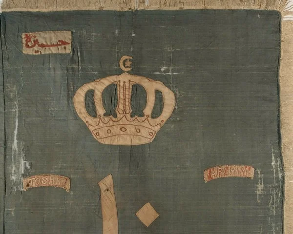 A fabric banner with a crown design, the words "Toshiku" and "Archway" on ribbons, and some worn edges.