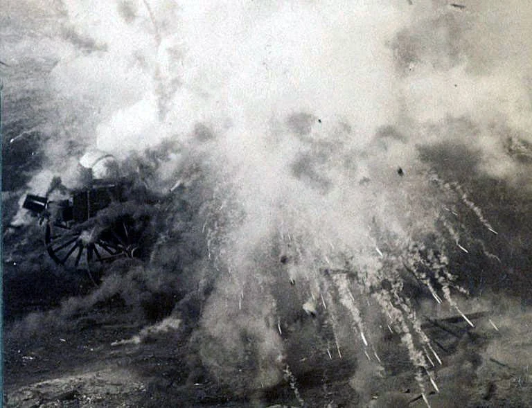 Historic black-and-white photograph of a cannon firing, with smoke and sparks surrounding it on a battlefield.