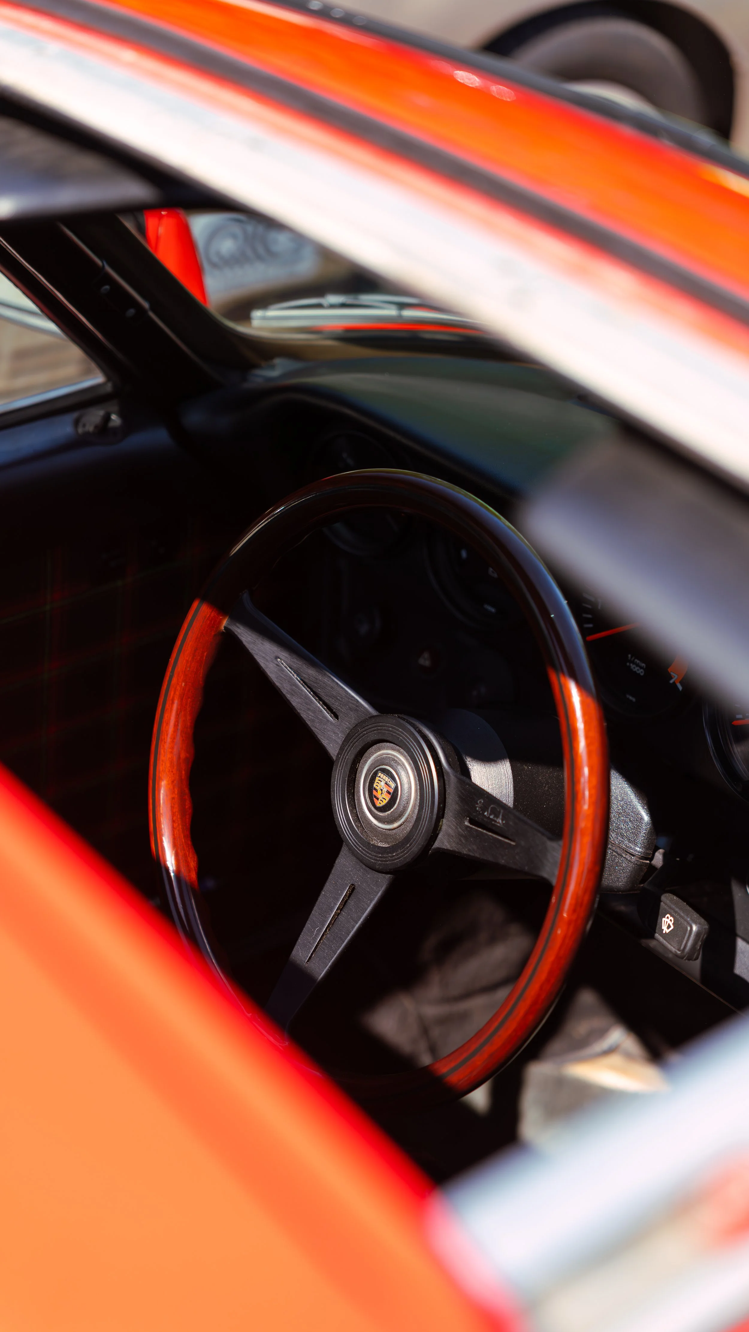 Interior view of a vintage Porsche car with a wooden steering wheel and dashboard gauges.