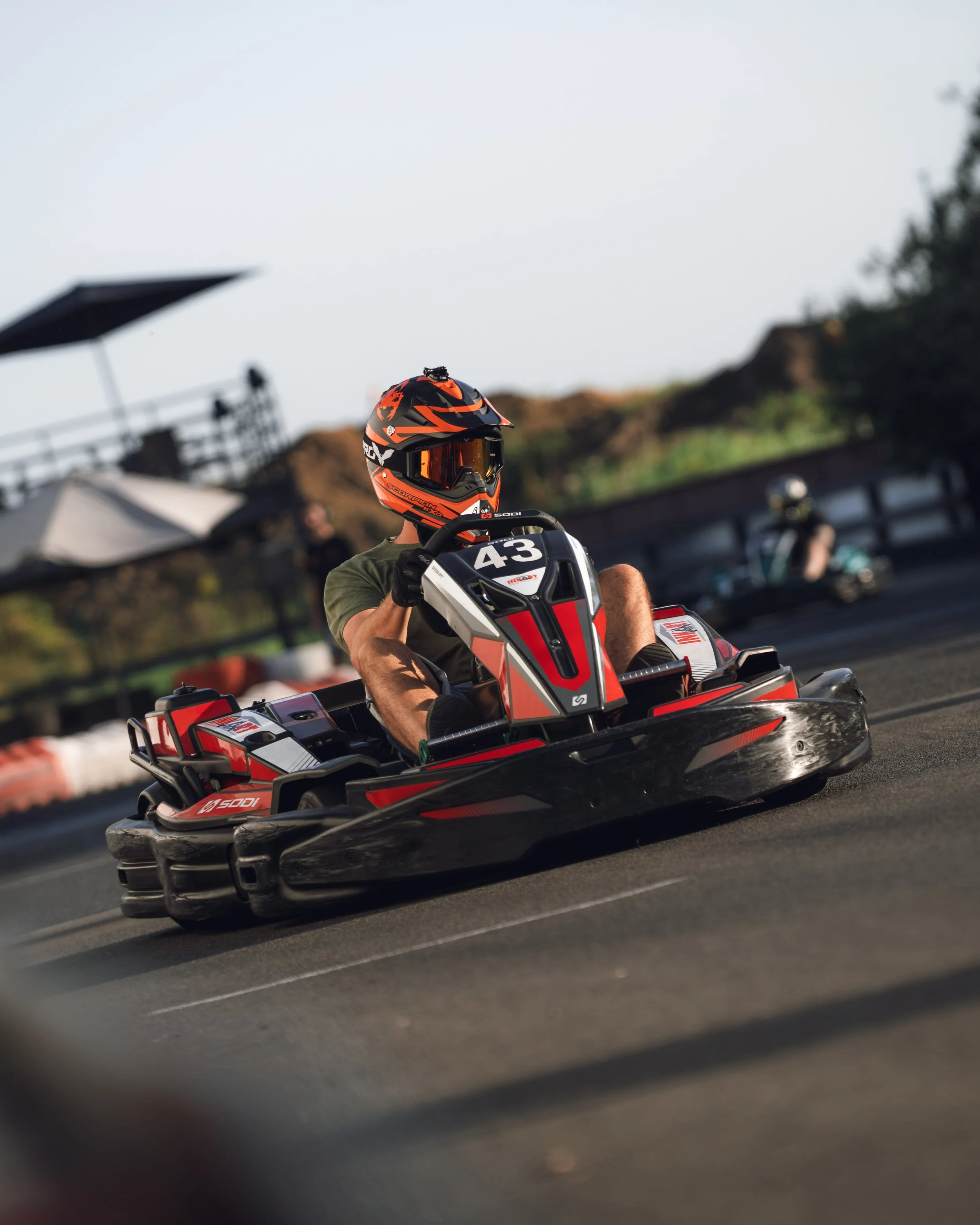Person riding an all-terrain vehicle (ATV) with a red and black helmet during a race or outdoor event.