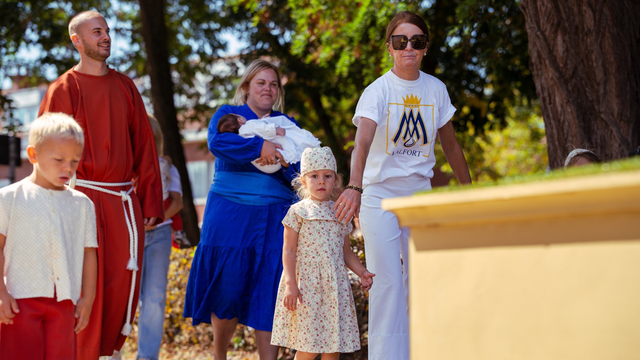 A group of people participating in an outdoor religious or cultural ceremony, with young children and adults gathered around.