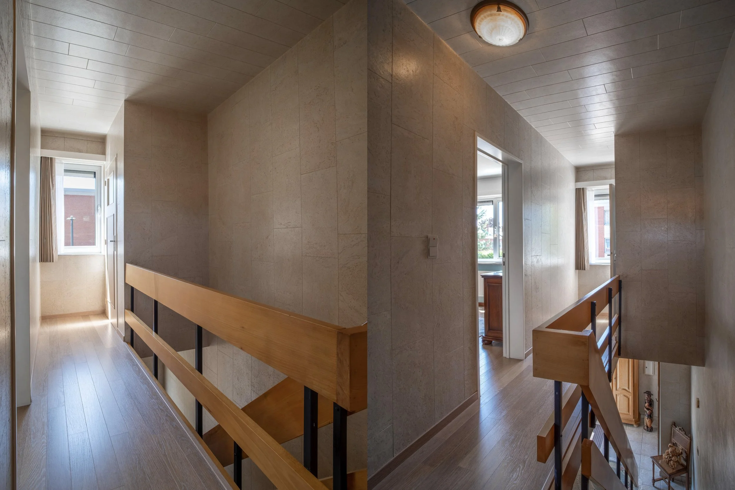 Interior view of a house with a hallway, wooden flooring, beige tiled walls, and several windows allowing natural light. A staircase with a wooden handrail and black metal supports is visible.