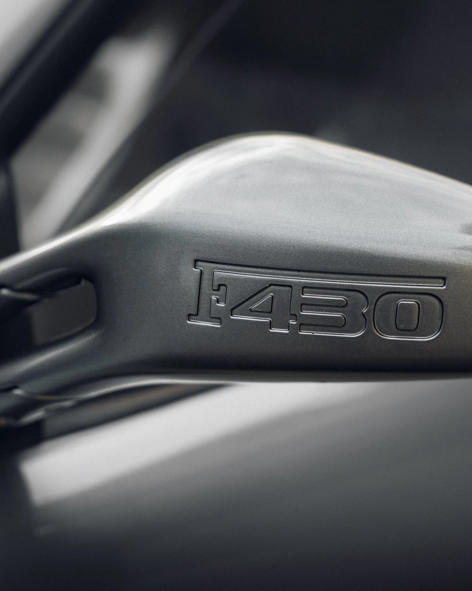 Close-up of a metallic model number F430 embossed on a car part.