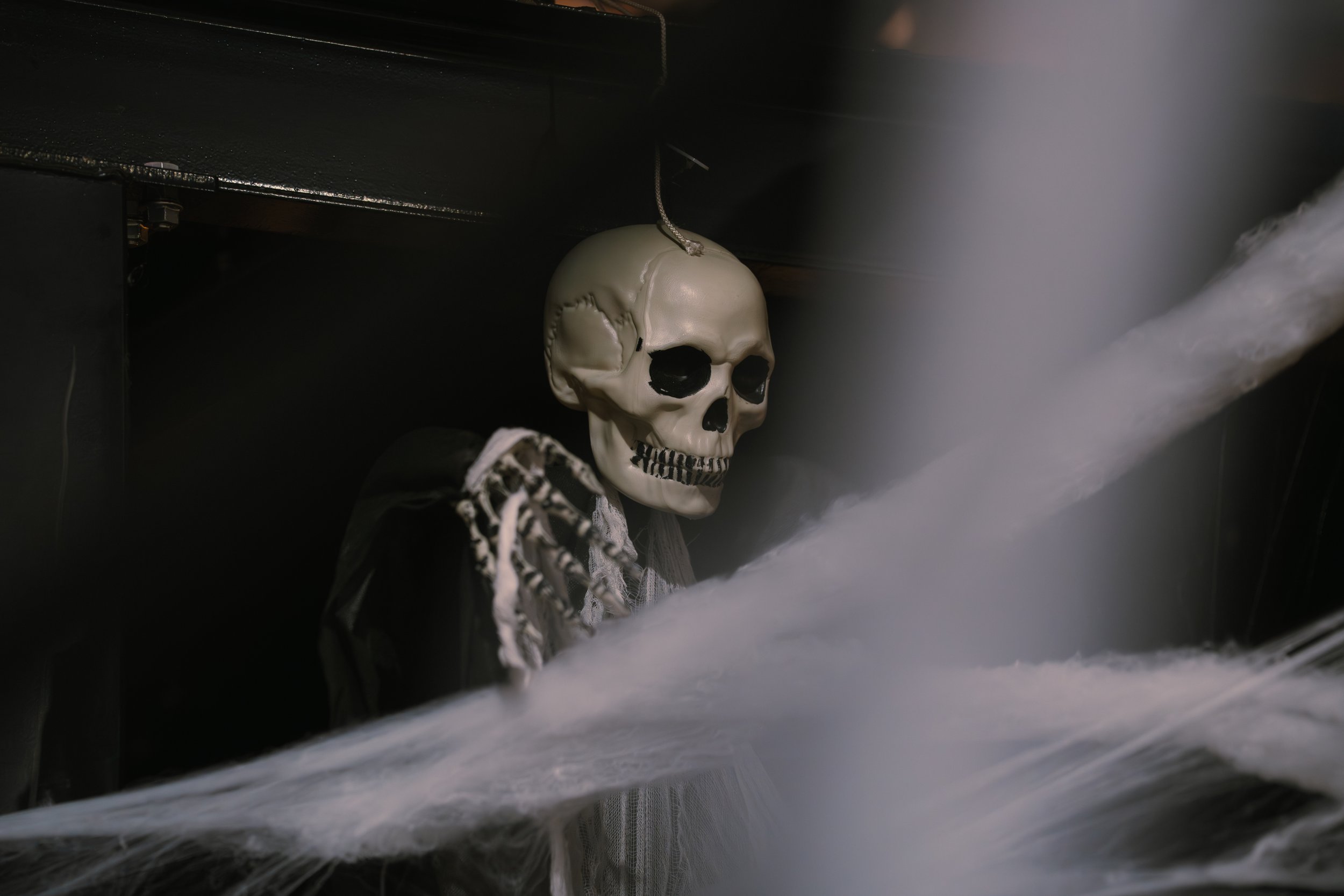A decorative skull hanging from a string amid a cloud of mist or fog in a dark setting.