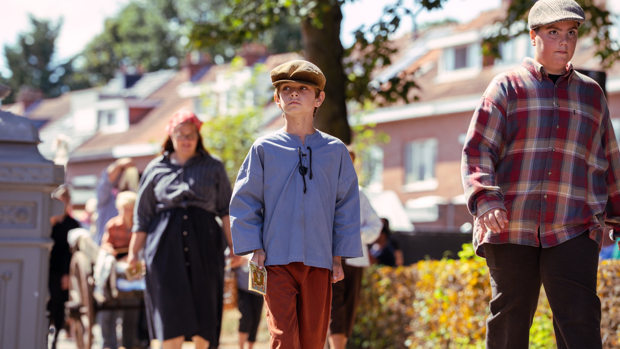 Children dressed in vintage clothing participating in a historical outdoor event or reenactment.