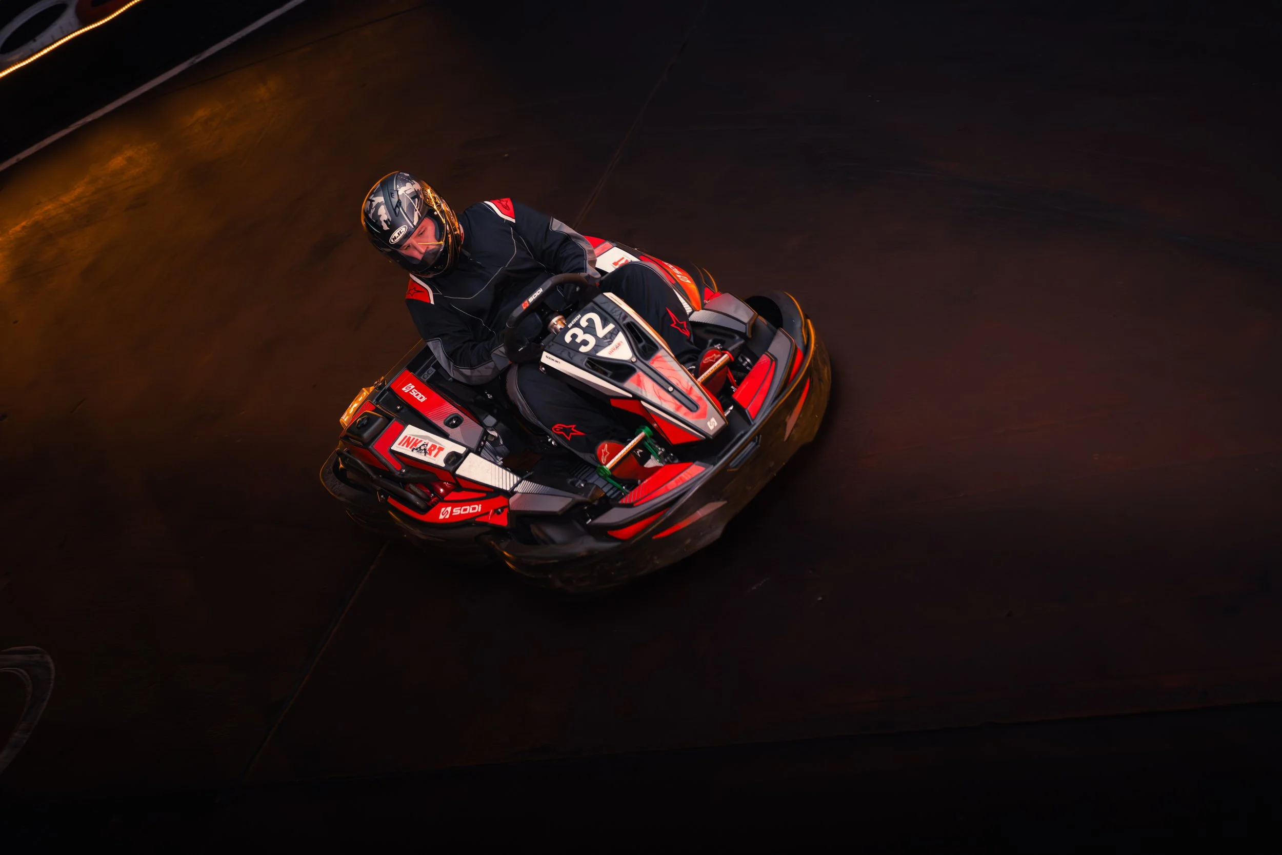 A person wearing a helmet and racing suit riding a red and black jet ski on dark water at night.