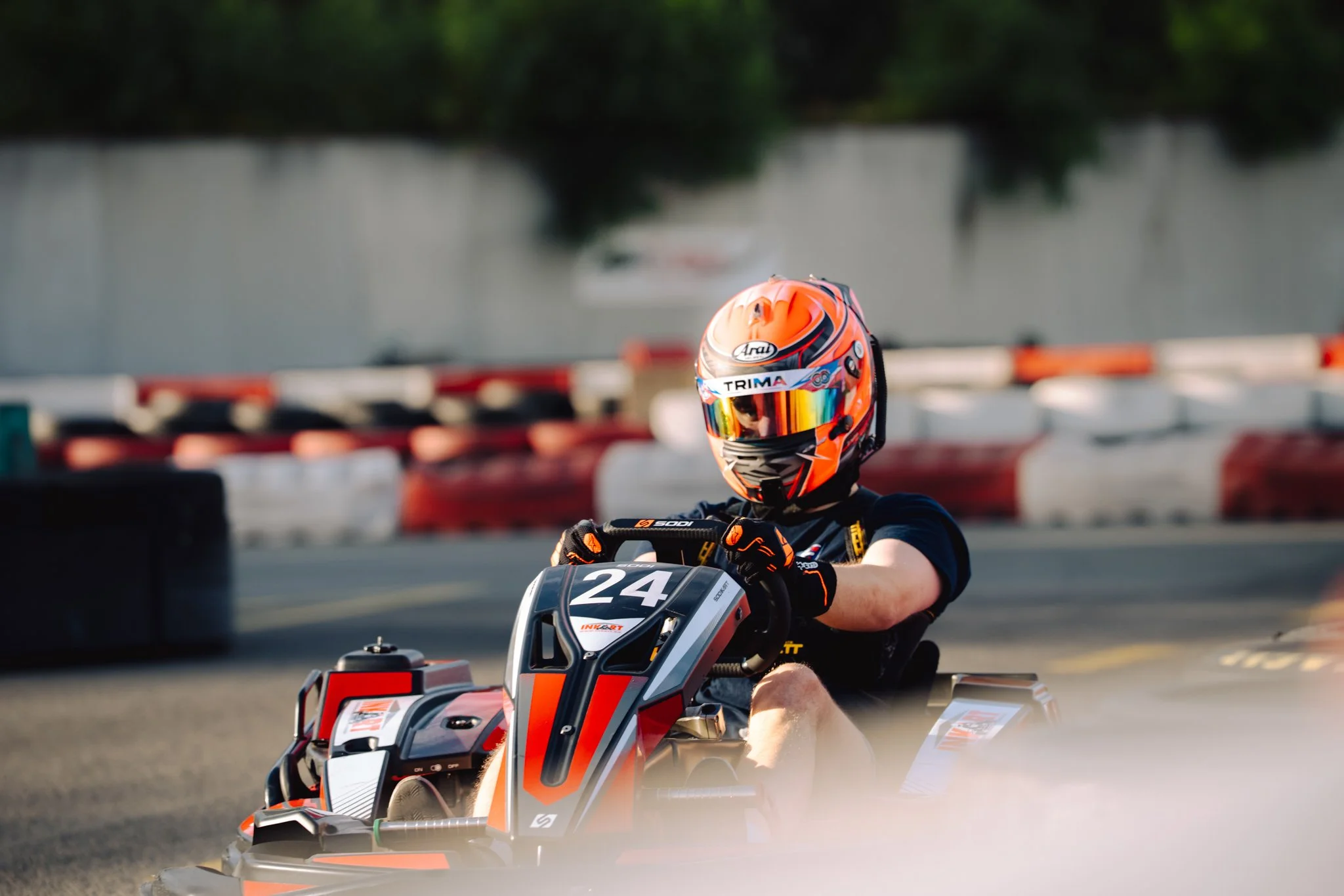 A person in racing gear and helmet driving a go-kart on a track.