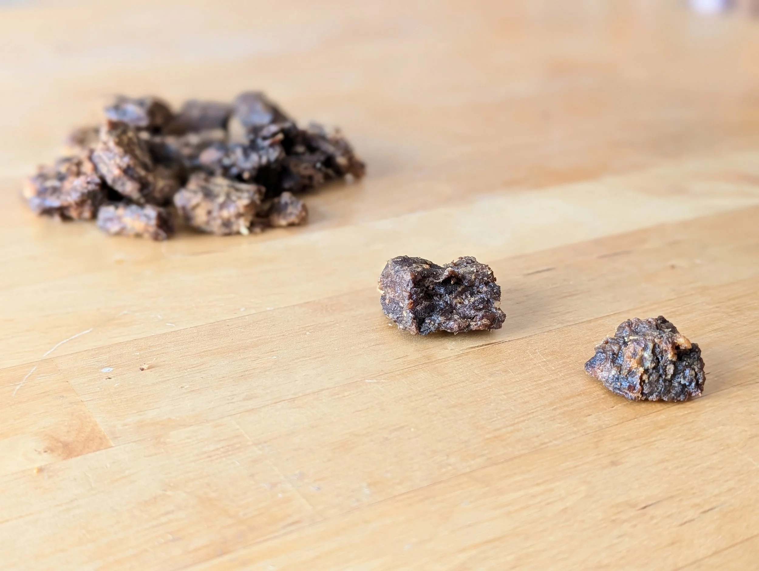 Mastication naturelle : Deux morceaux de cube de canard sur une surface en bois avec un tas de cubes en arrière-plan.