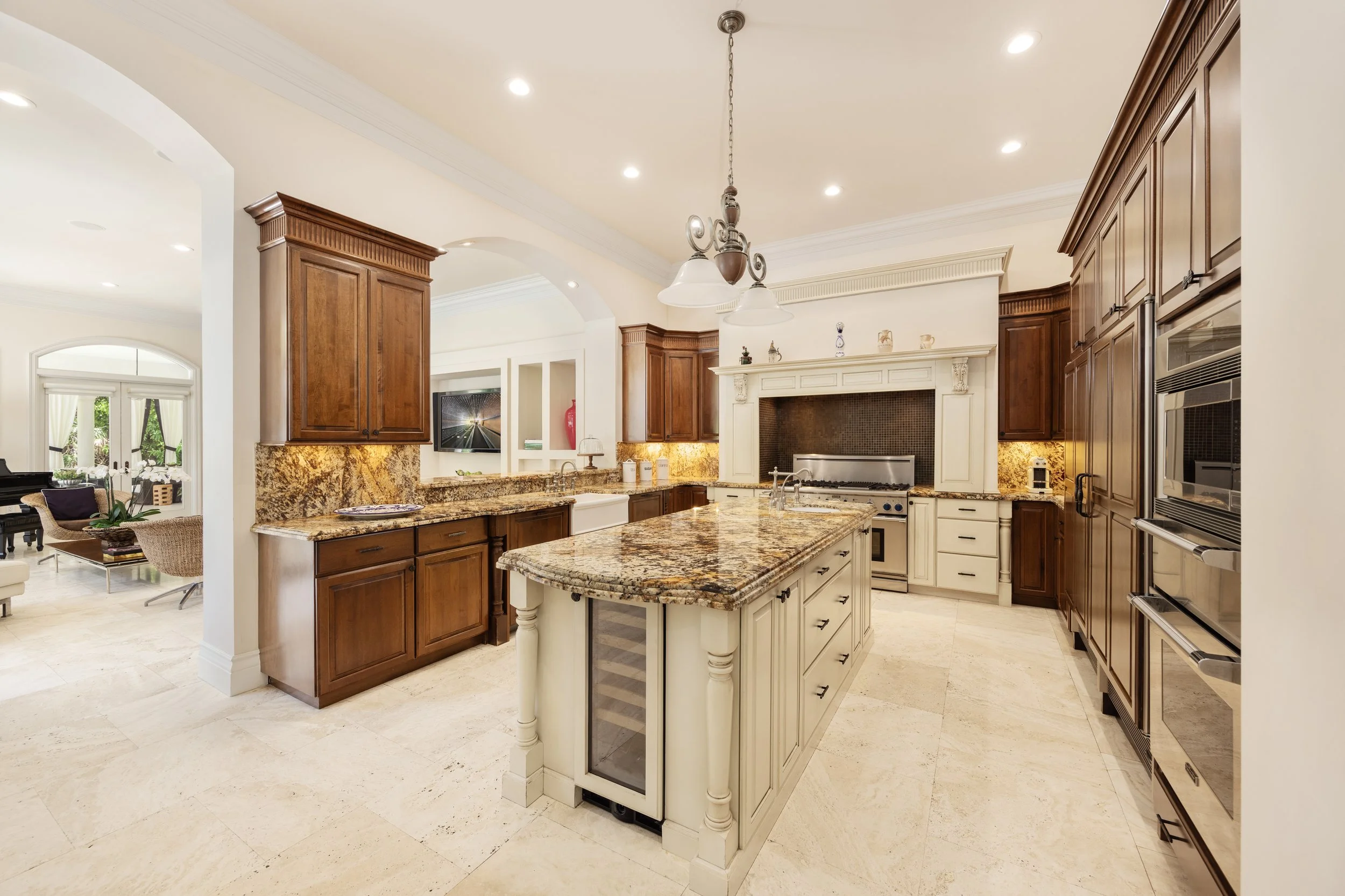 Luxury kitchen with granite countertops, wooden cabinets, an island with a wine cooler, and stainless steel appliances.