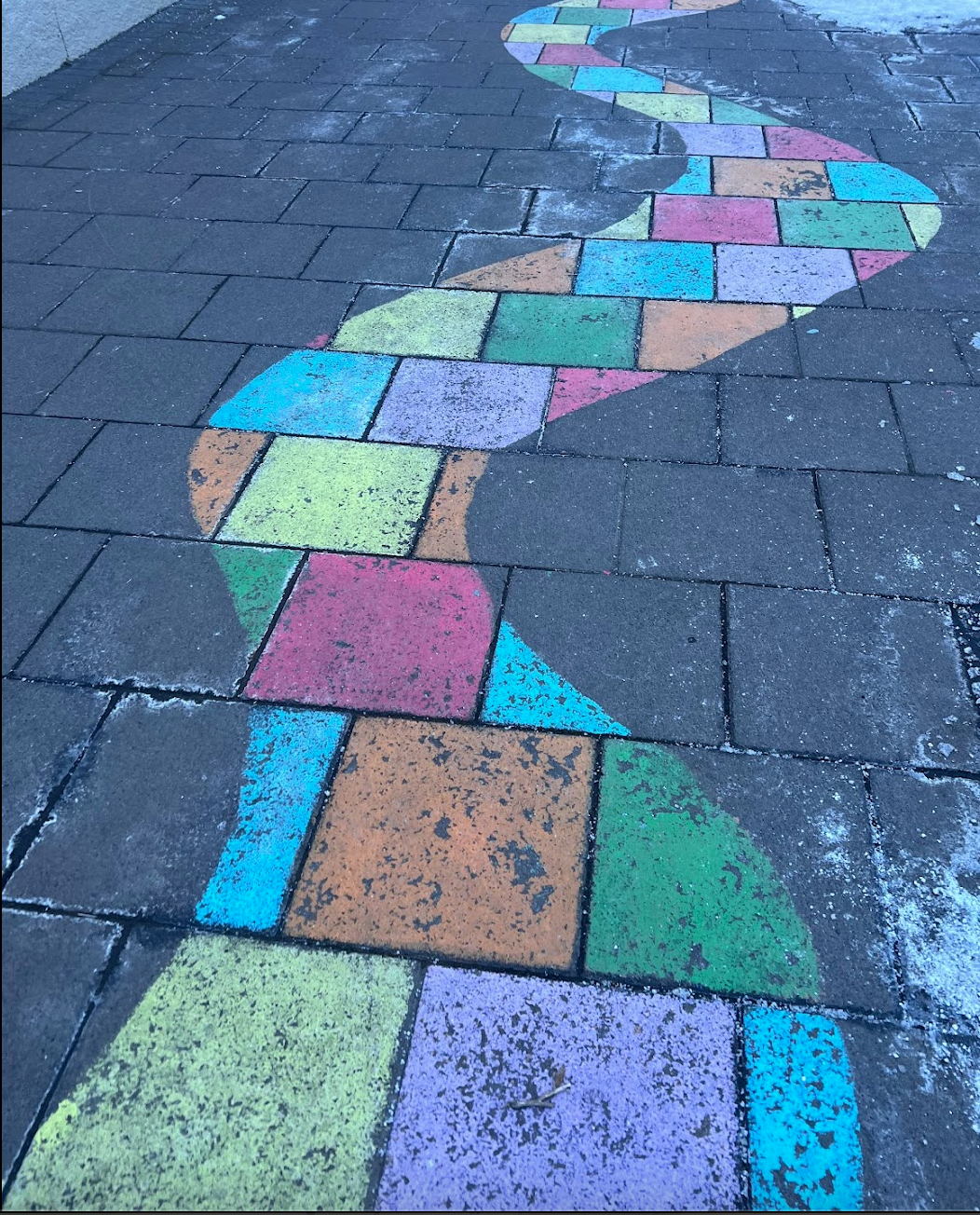 Colorful chalk drawing of a winding path on pavement, with geometric shapes in various colors.
