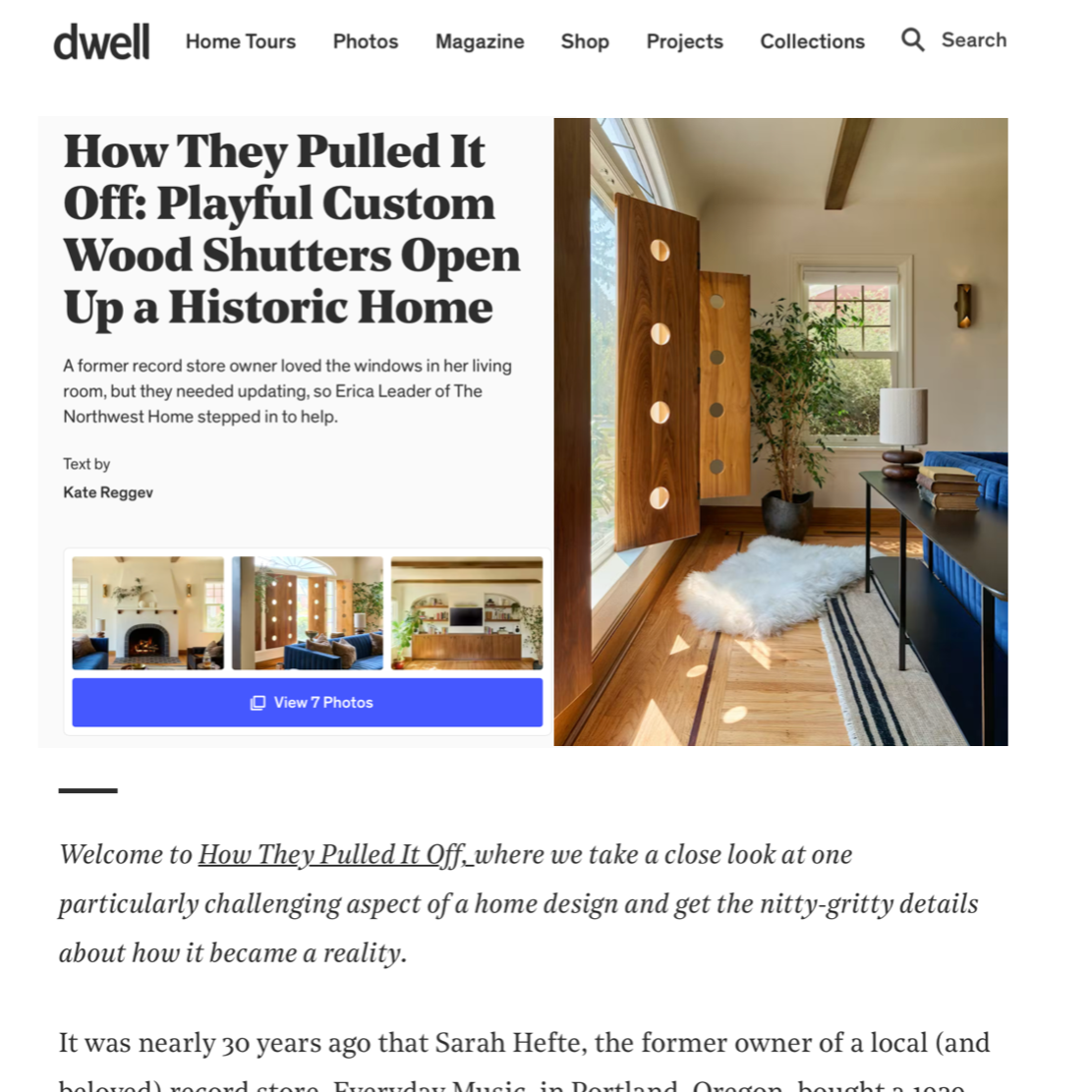 Interior of a home with a large window, custom wood shutters with circular cutouts, a potted plant, a blue sofa, a table with a lamp and books, and a white shag rug.