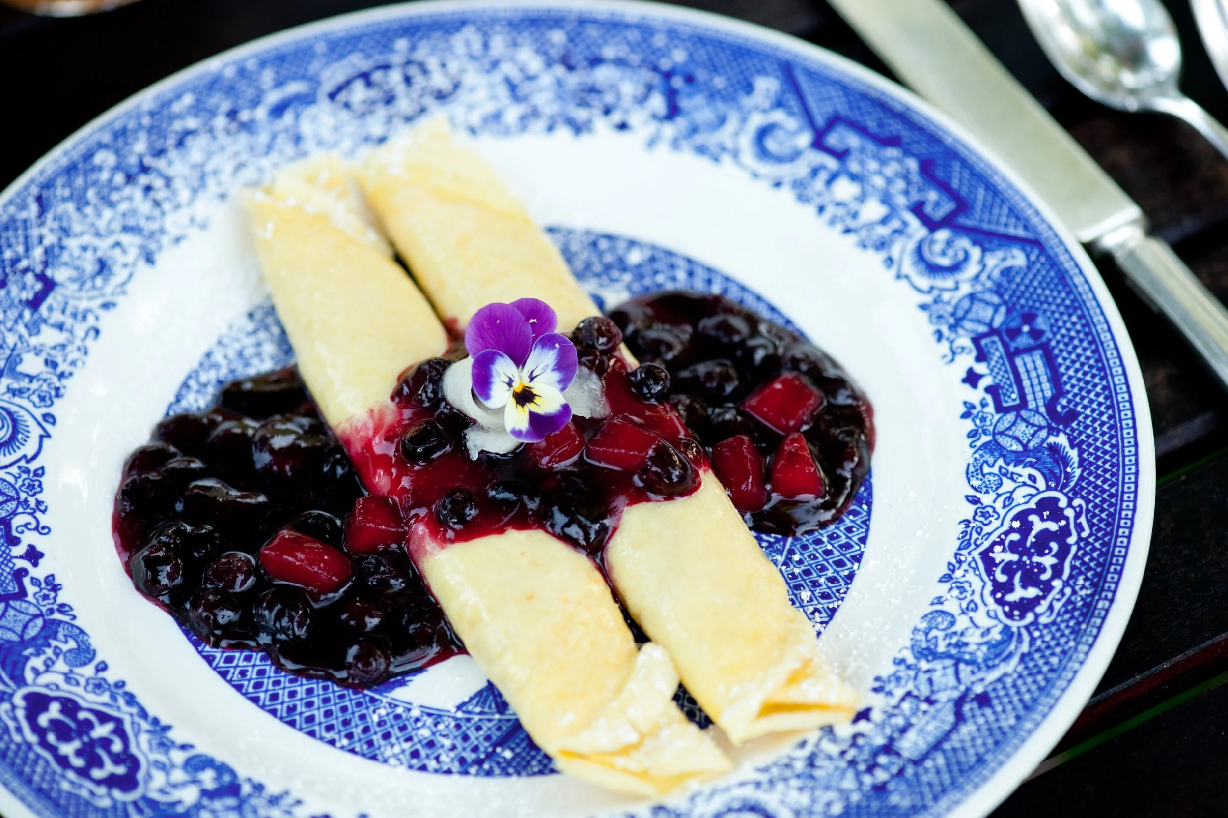 Huckleberry-pear crepes served on historic Blue Willow china from Glacier National Park's Great Northern Railway era.