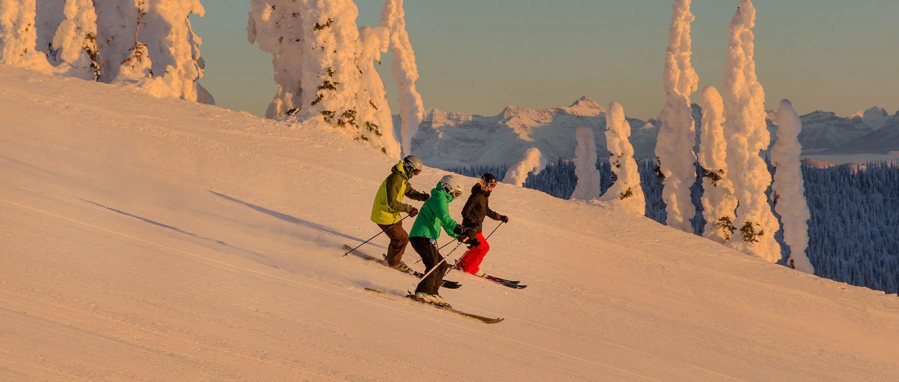 Skiing in the Alpinglow at Whitefish Mountain Resort with snow ghosts and peaks of the Northern Rockies in the distance.