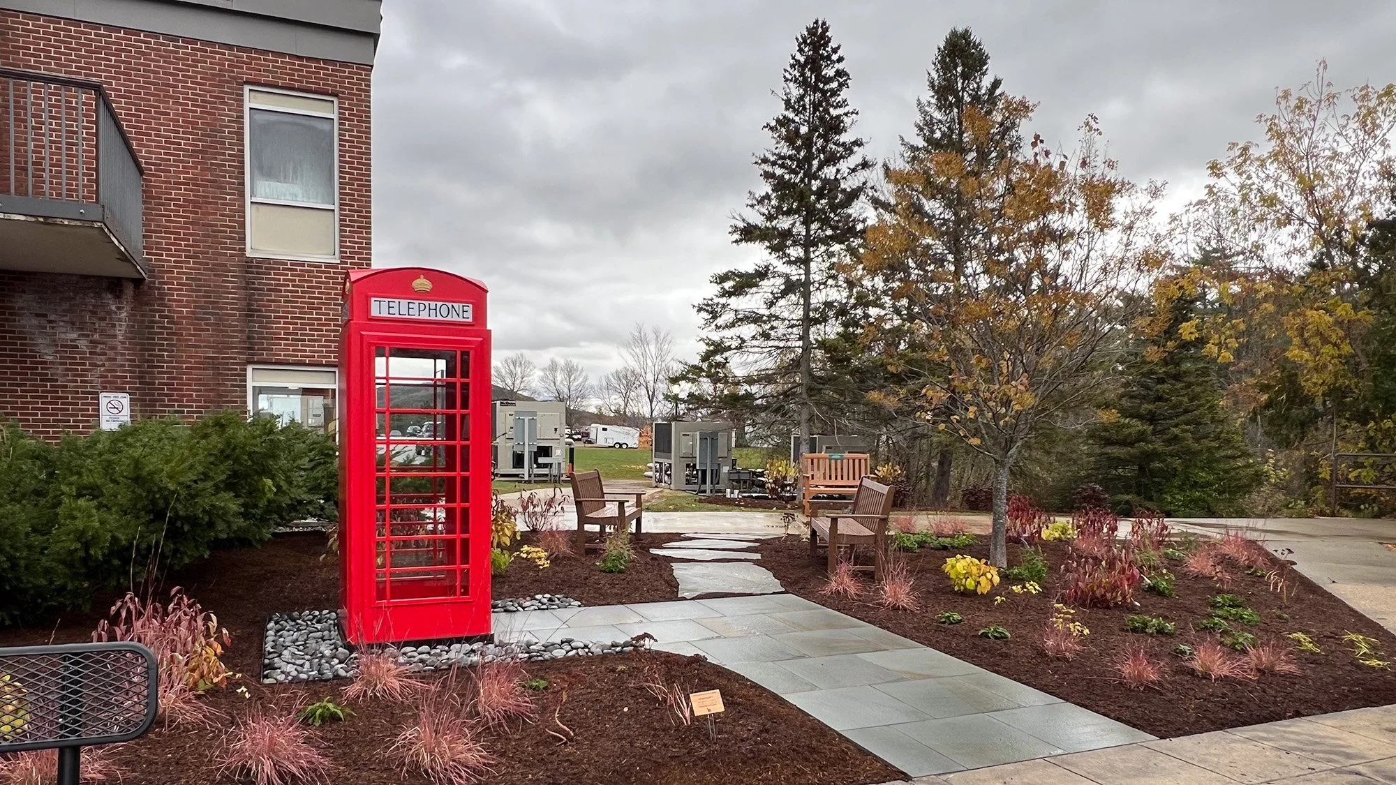 The renewed garden includes a central path and benches for quiet sitting. Visitors can leave memorial pebbles at the base of the wind phone.
