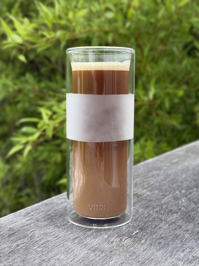 A tall clear glass holds an iced coffee