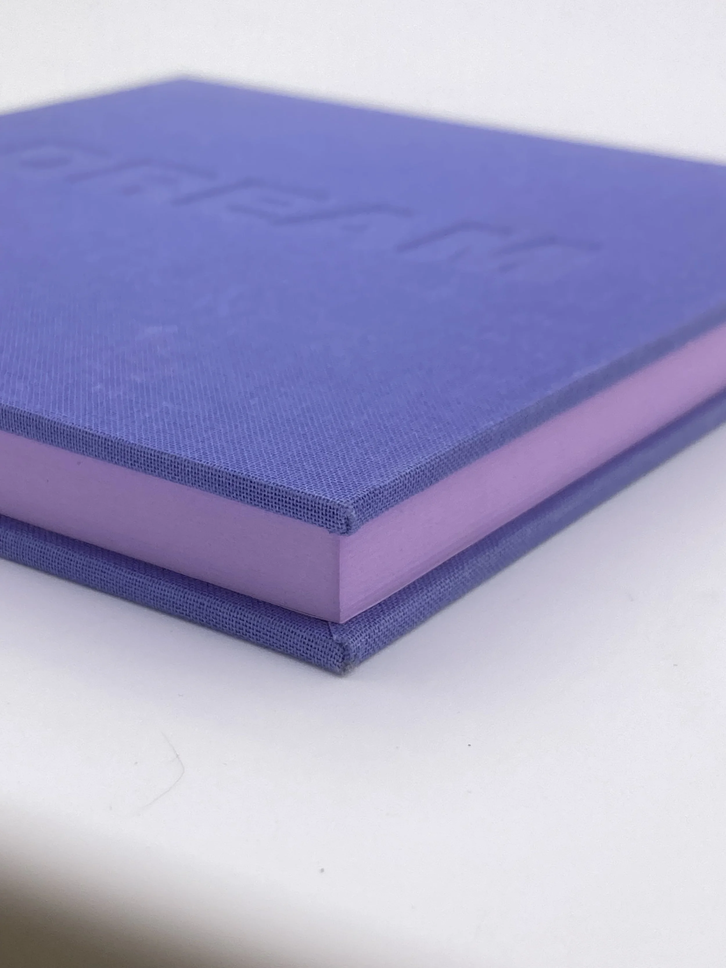 The corner of a indigo notebook with purple pages. 