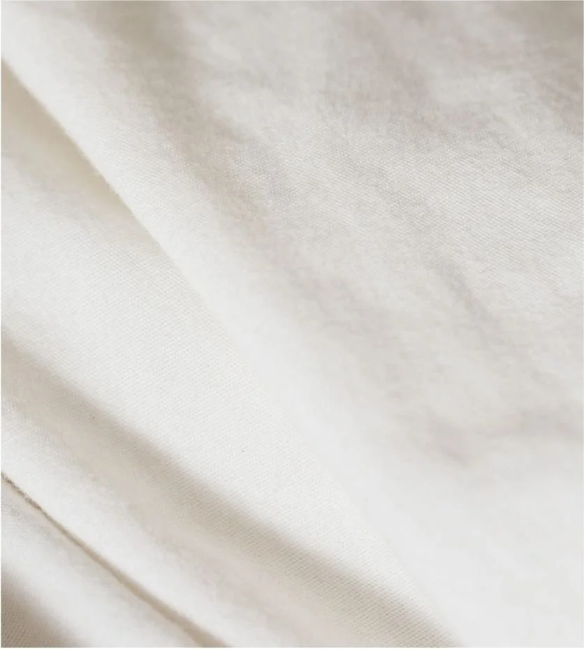 Close-up of cream-colored fabric with soft folds and smooth texture.