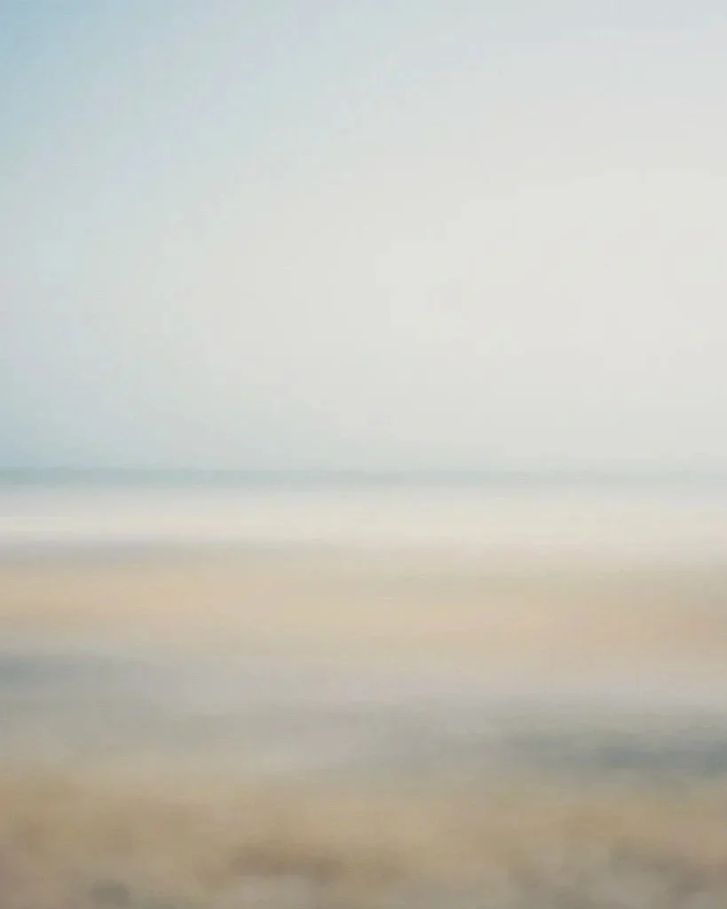 Abstract image of a beach with gentle waves and a calm sea under a light sky, short