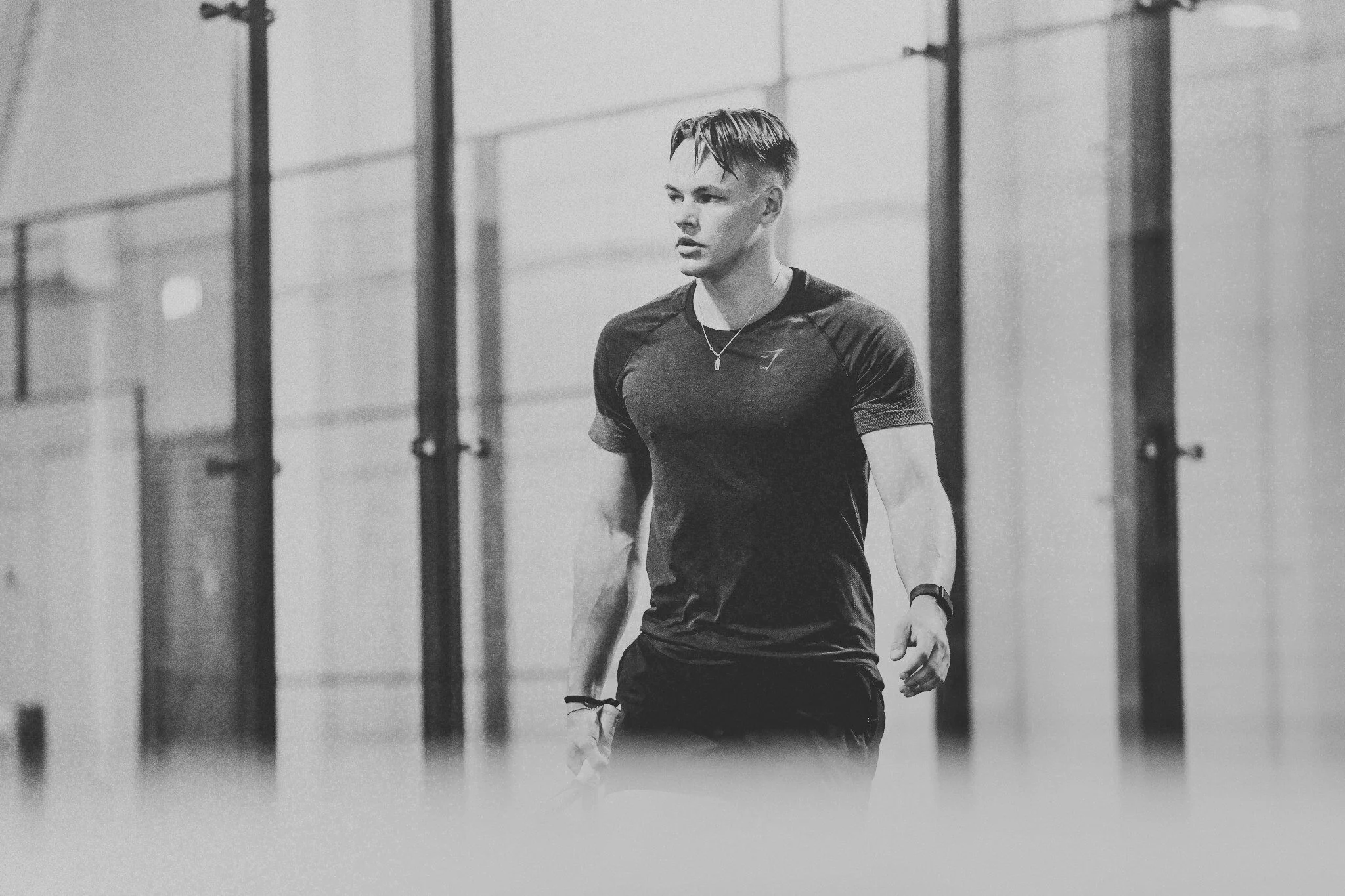 A young man in athletic clothing standing inside a gym, looking to the side.